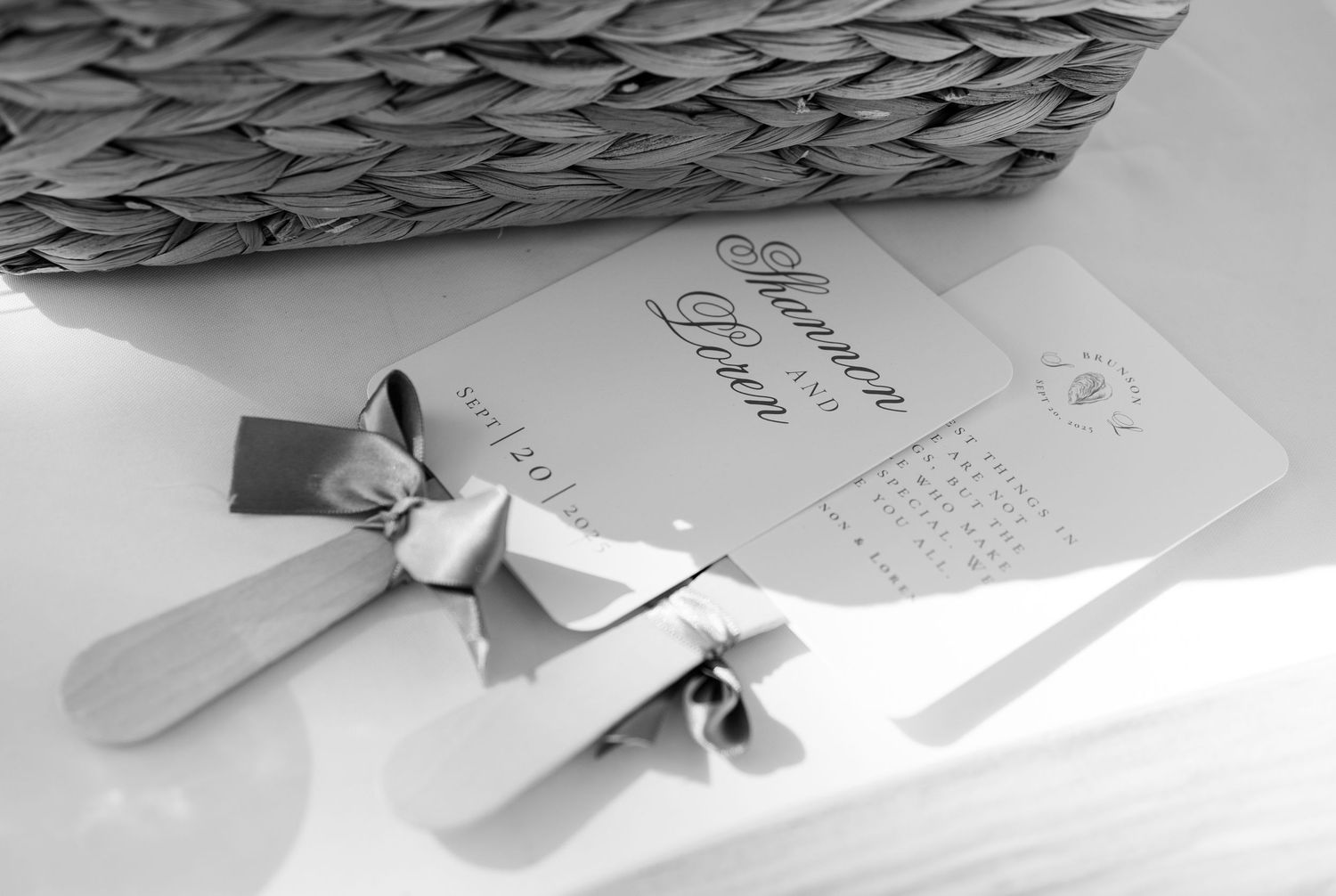 Elegant wedding invitation with a silver bow ribbon displayed in black and white.