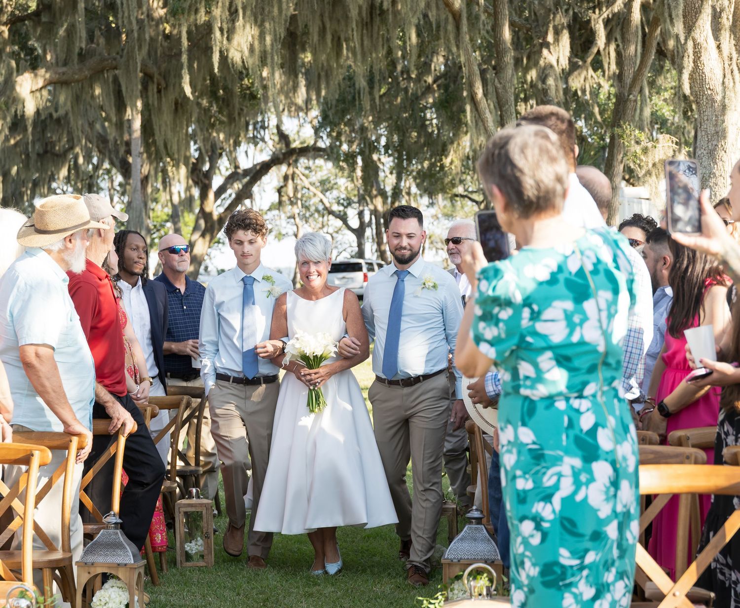 Wedding guests mingle and dance outdoors at a rustic garden reception with turquoise bridesmaids dresses.
