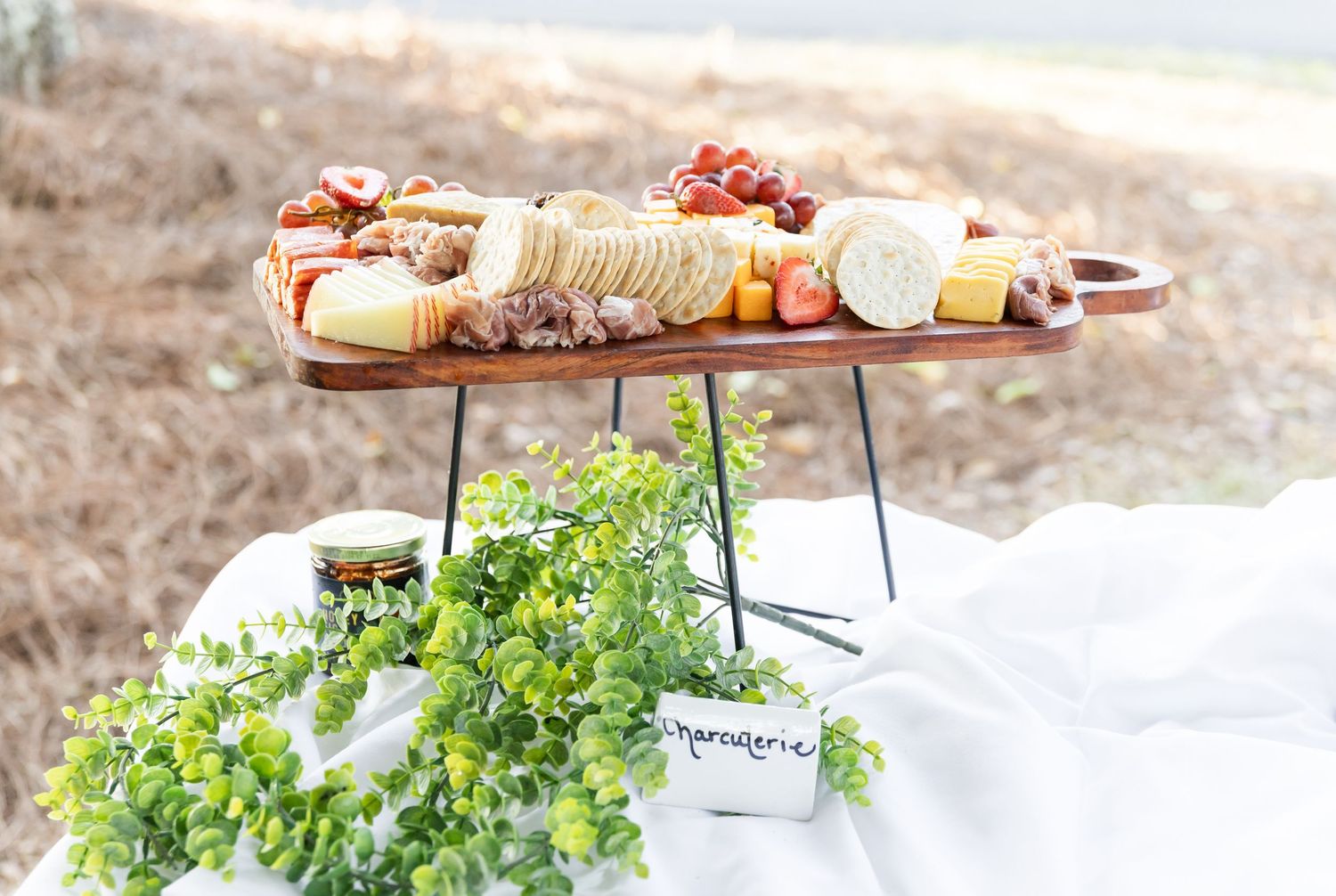 Charcuterie board with assorted cheeses, fruits, and meats displayed on a rustic wooden surface.