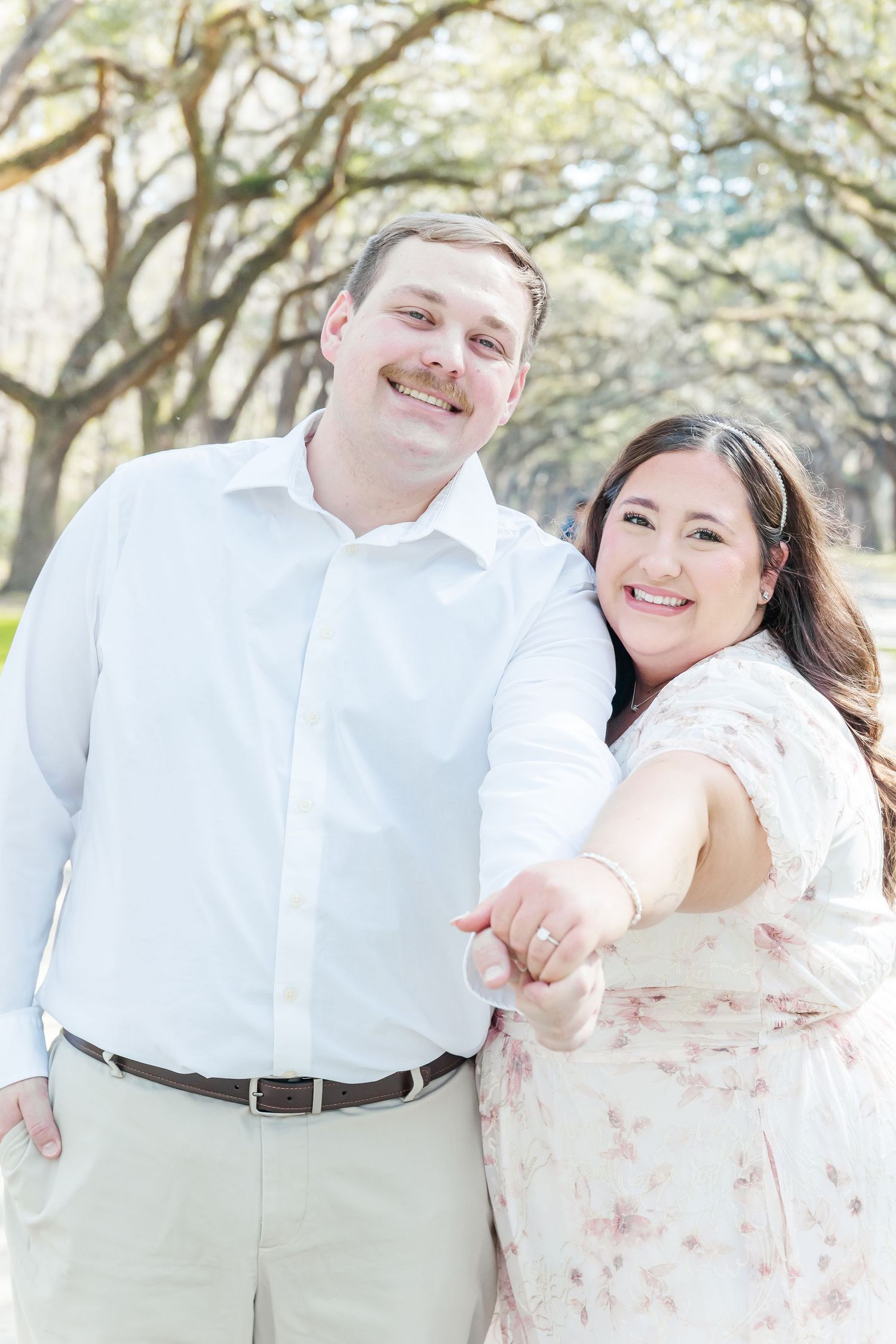 Couple in white outfits sharing a joyful moment during their engagement photoshoot.