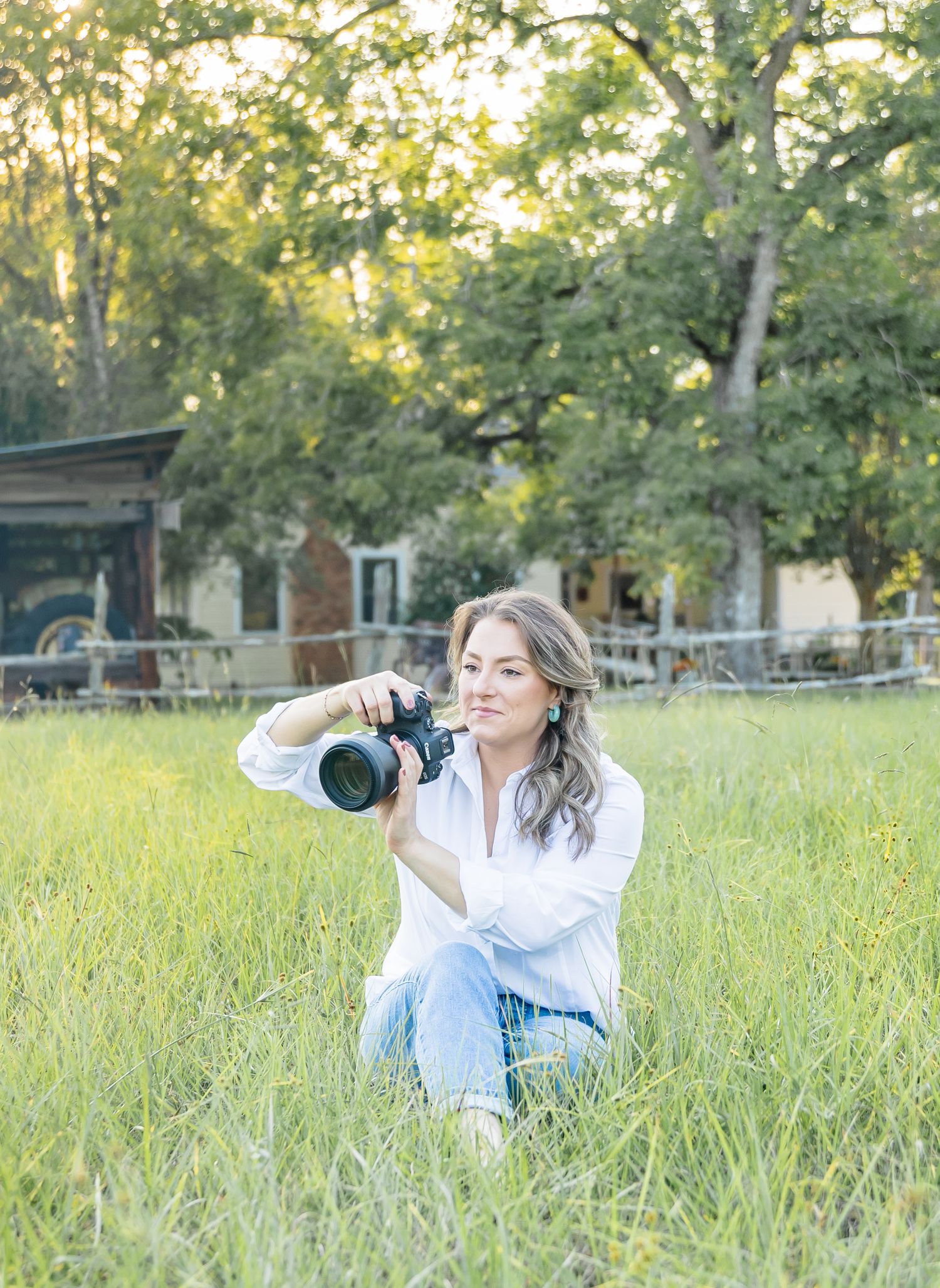 Person in a white button-down shirt lies in tall grass with playful poses during a golden hour outdoor photo session.