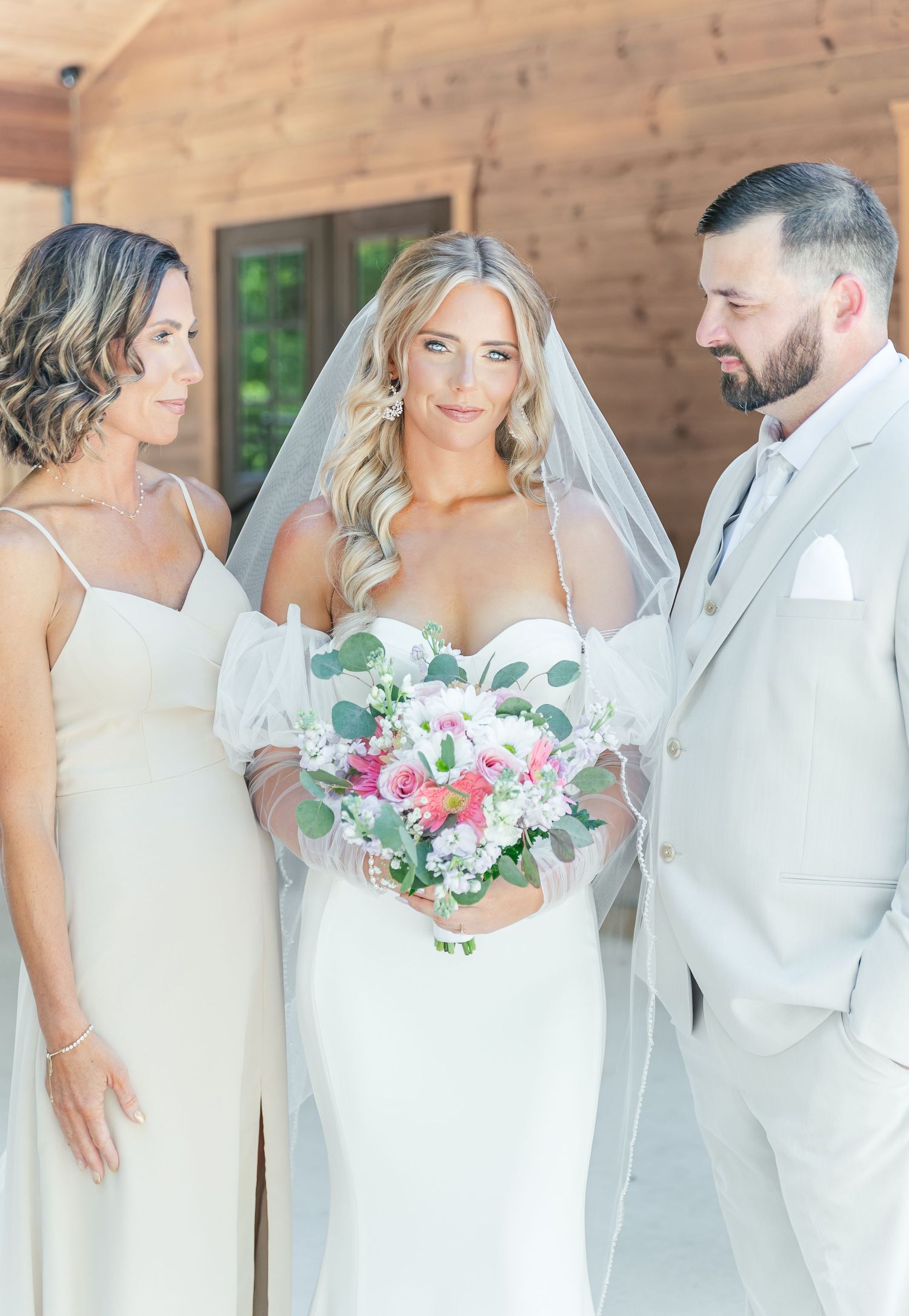 Intimate bridal party portrait with soft lighting and pink floral bouquet.