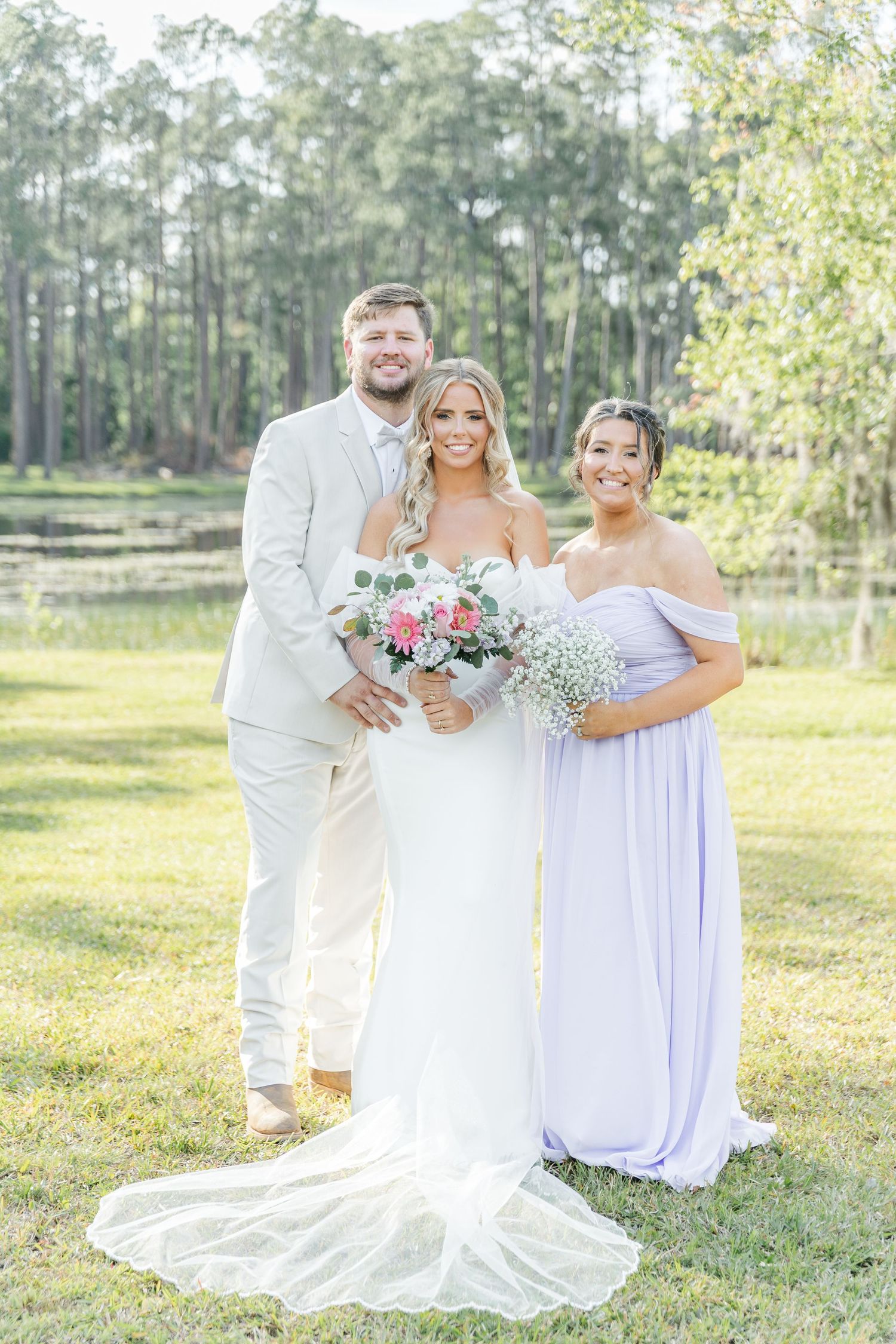 Soft romantic wedding photo with bridal party in white and lavender holding fresh floral bouquets.