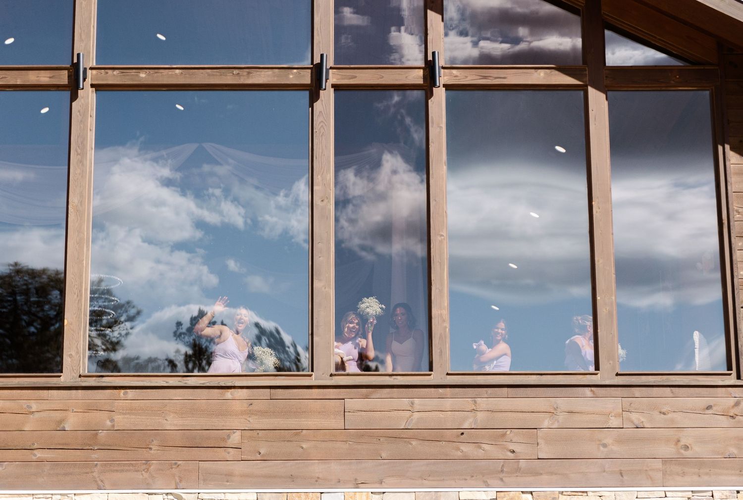 View through large windows of a wedding venue with cloudy blue sky and reflections.