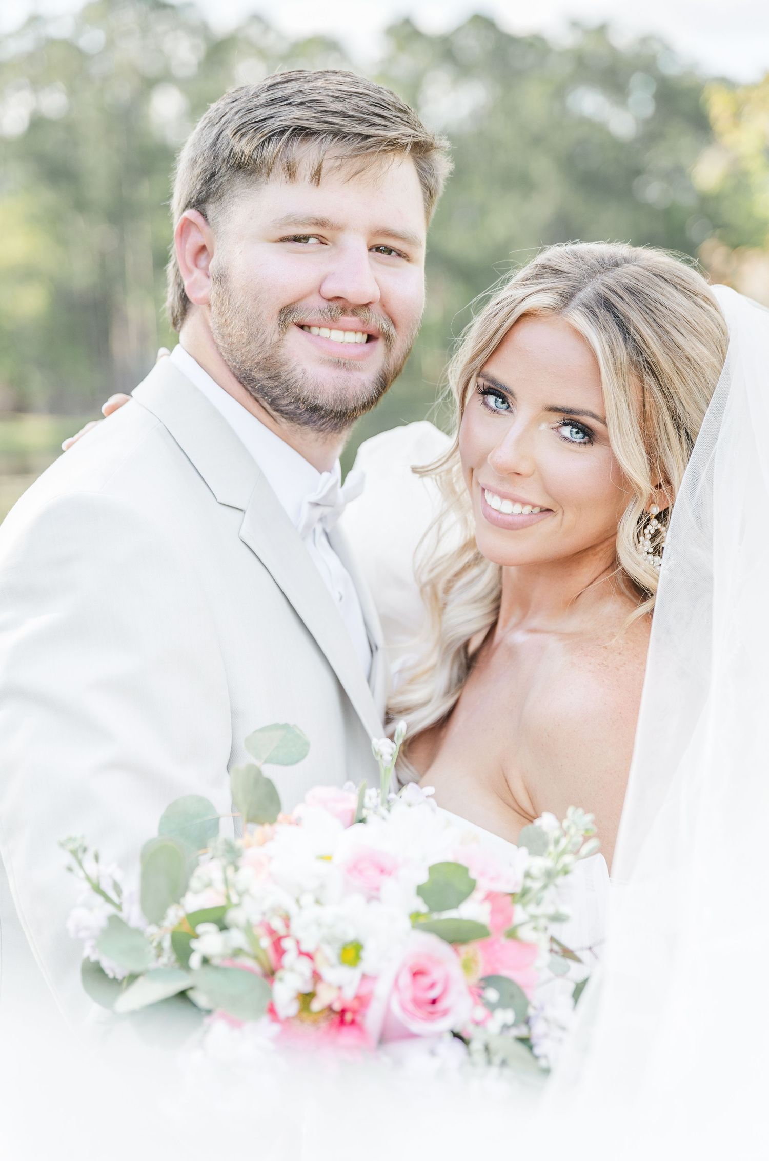 Bright and cheerful wedding portrait featuring happy couple with elegant floral arrangement.
