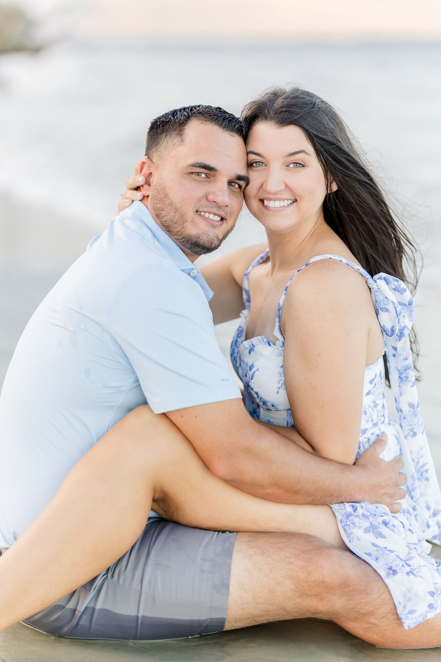 A couple in light blue and floral outfits share romantic poses during an outdoor photo session.