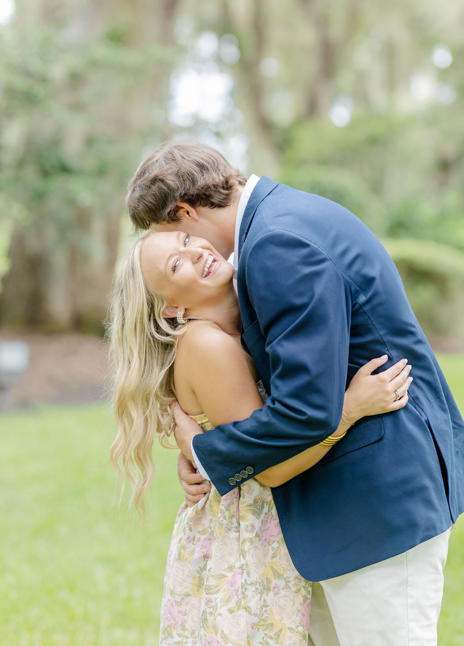 A romantic couple shares an intimate dip pose in a lush outdoor garden setting while wearing formal attire.
