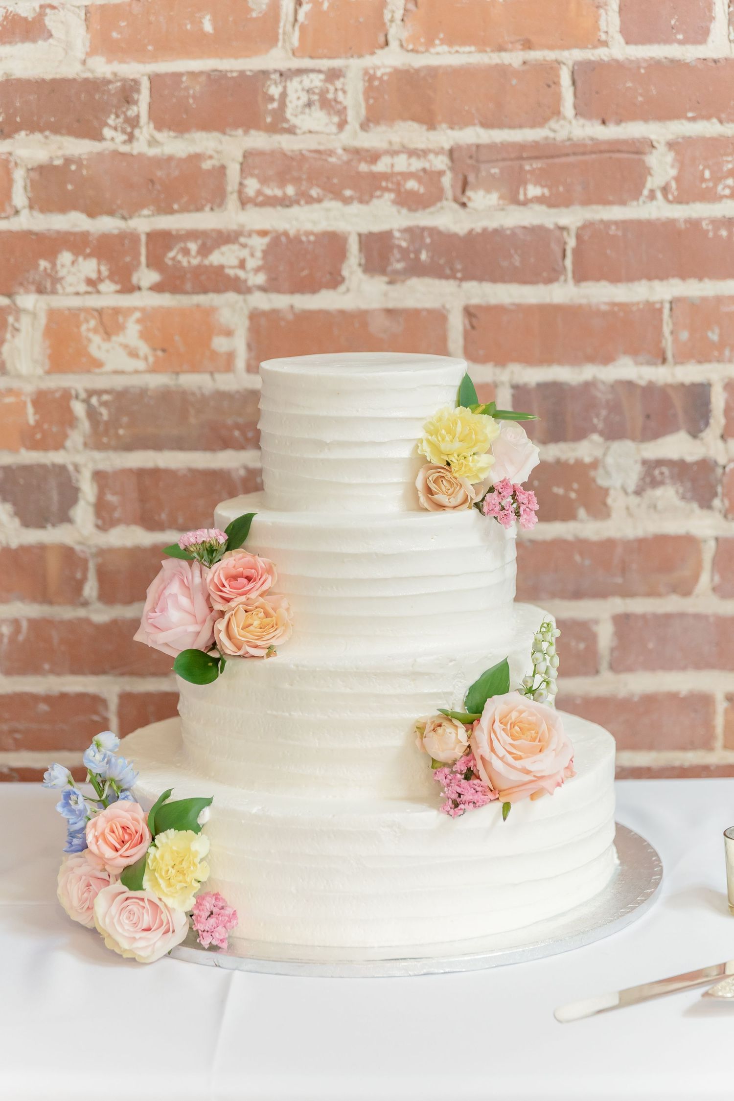 White textured wedding cake decorated with delicate pink and peach roses.