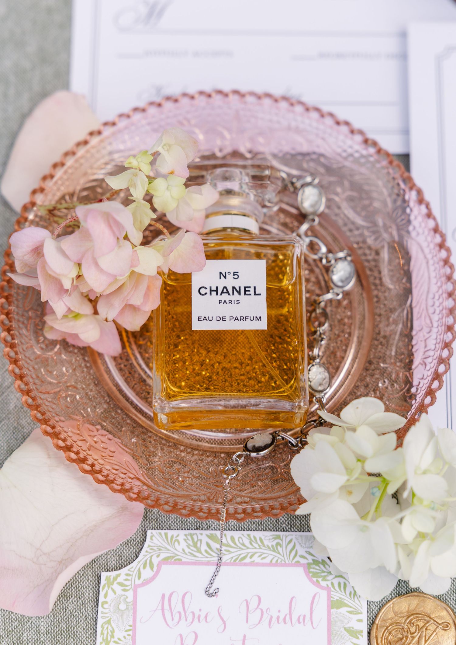Chanel No. 5 Eau de Parfum bottle on a pink glass plate with flowers at a bridal party setting.