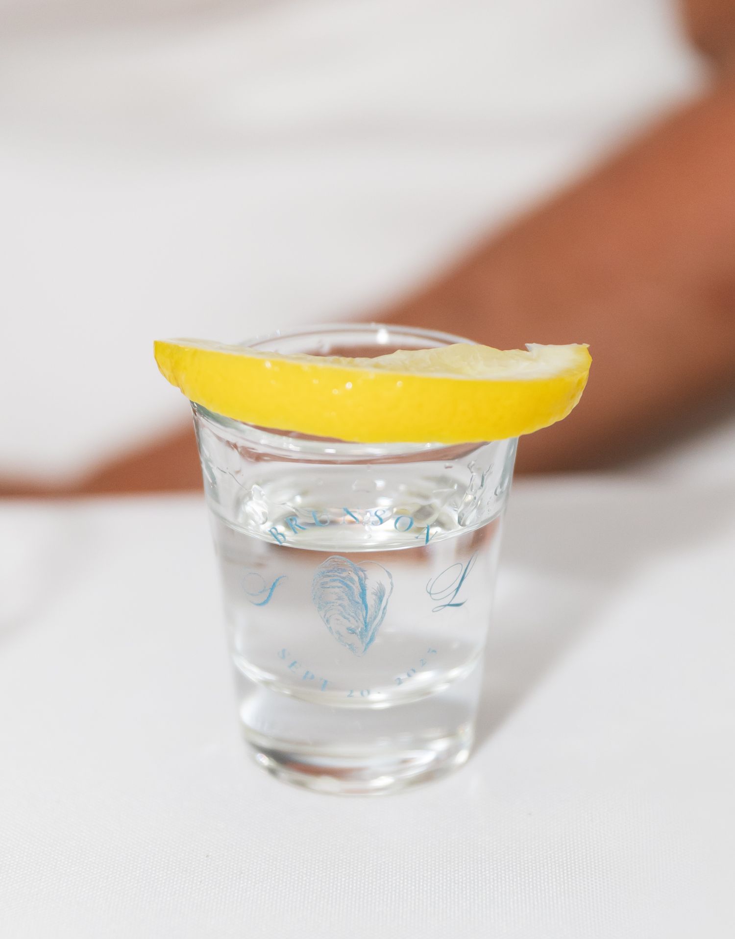 A sequence of small glass bowls with lemon wedges being placed as garnish on top of clear liquid.