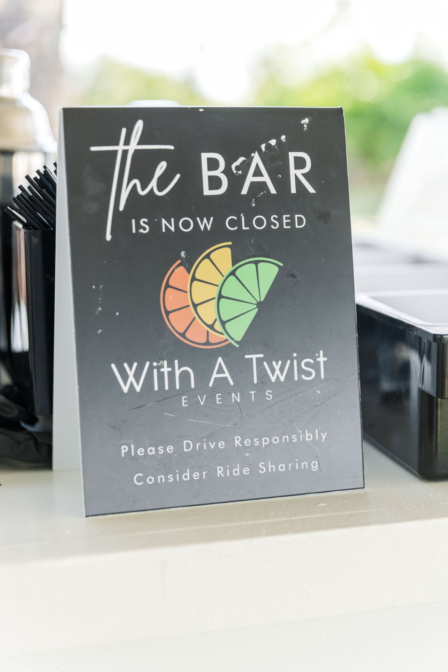 Black signage for 'The Bar' with colorful logo displayed at an event venue.