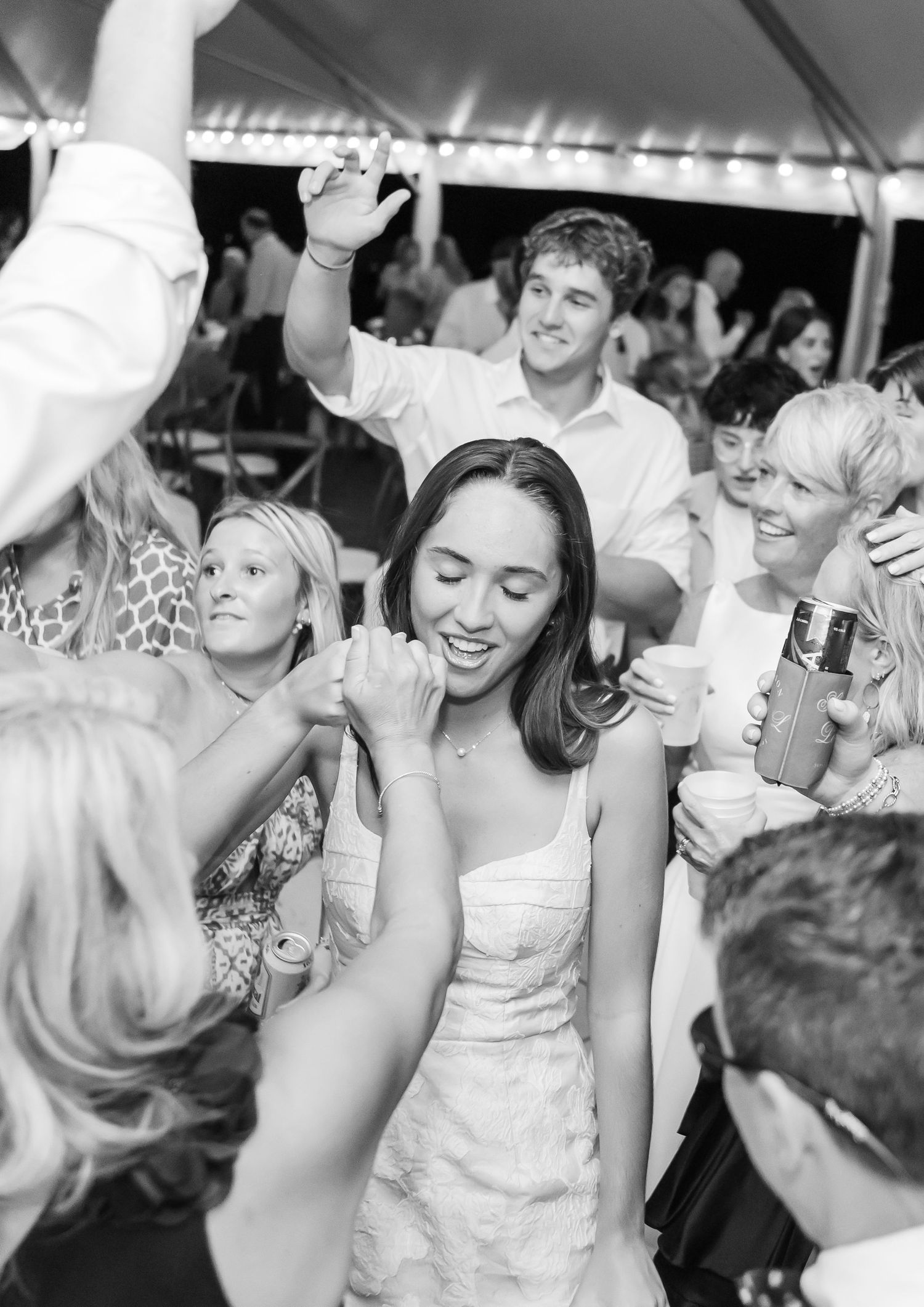 Wedding guests dancing and celebrating on a crowded dance floor at a reception party.