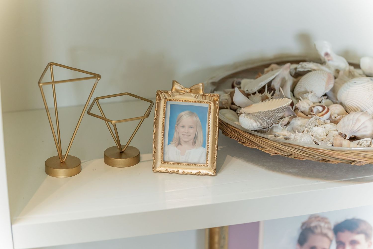 A collection of vintage teacups, saucers, and decorative items displayed on white shelving against a wall.