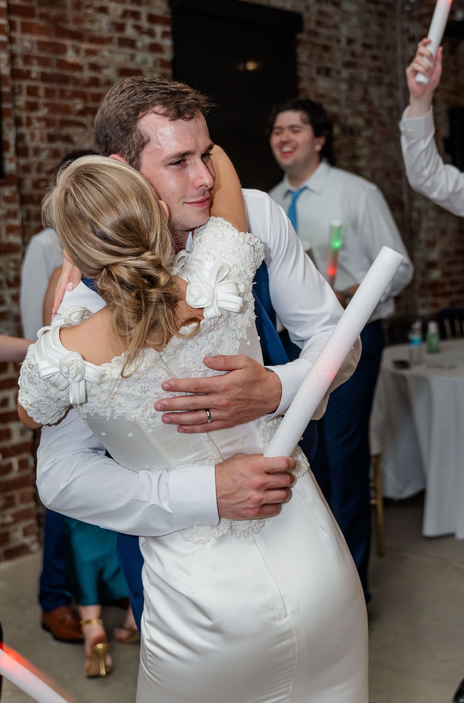 Couples share romantic slow dances at a wedding reception in an industrial brick-walled venue.