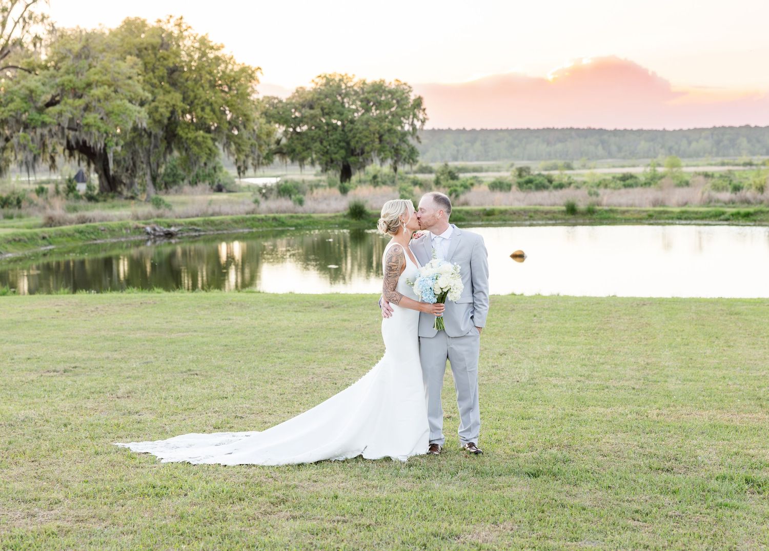Bride and groom sharing a romantic moment by a lake at golden hour sunset in an outdoor wedding.