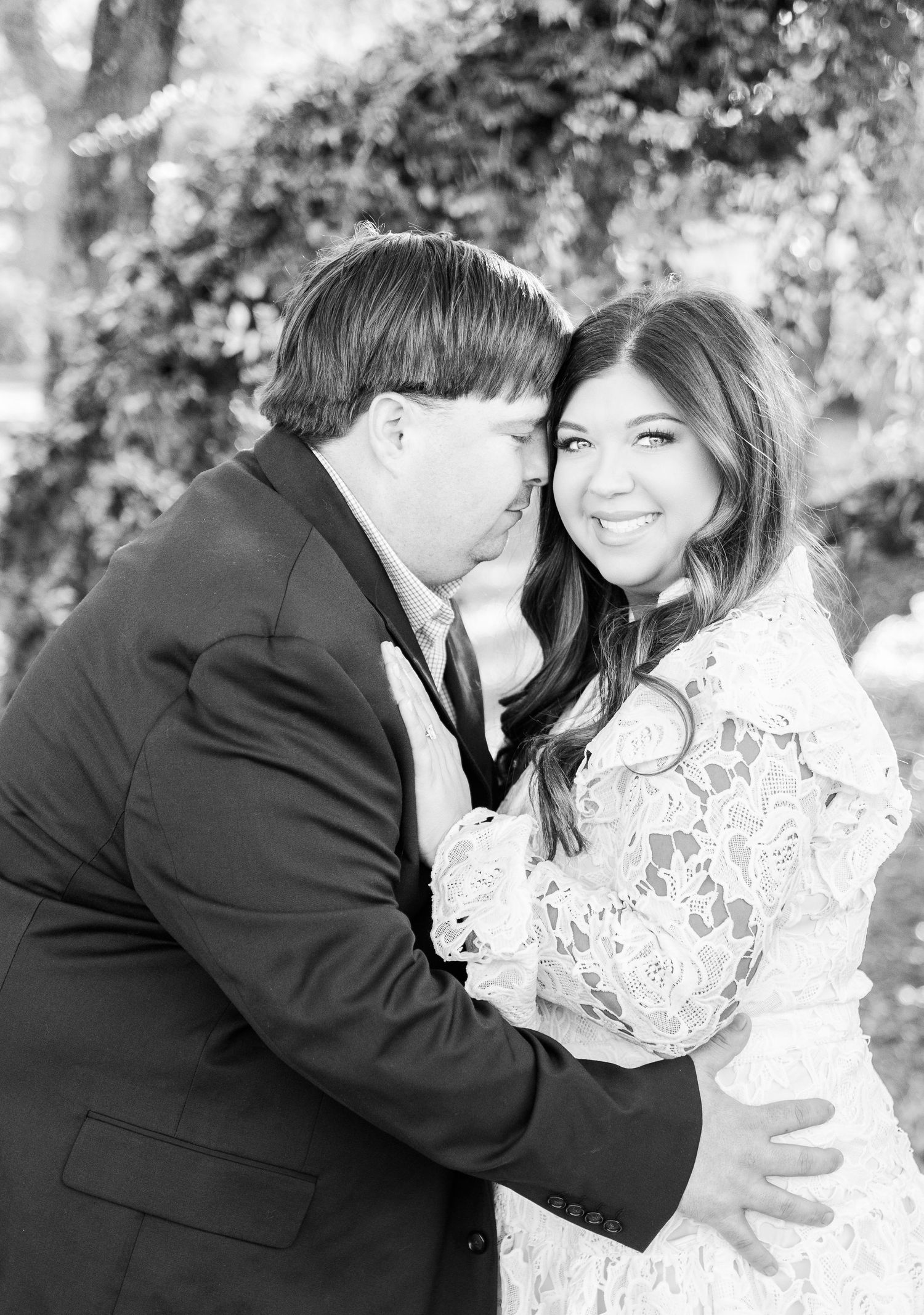 A joyful black and white engagement photo capturing a couple's embrace outdoors.