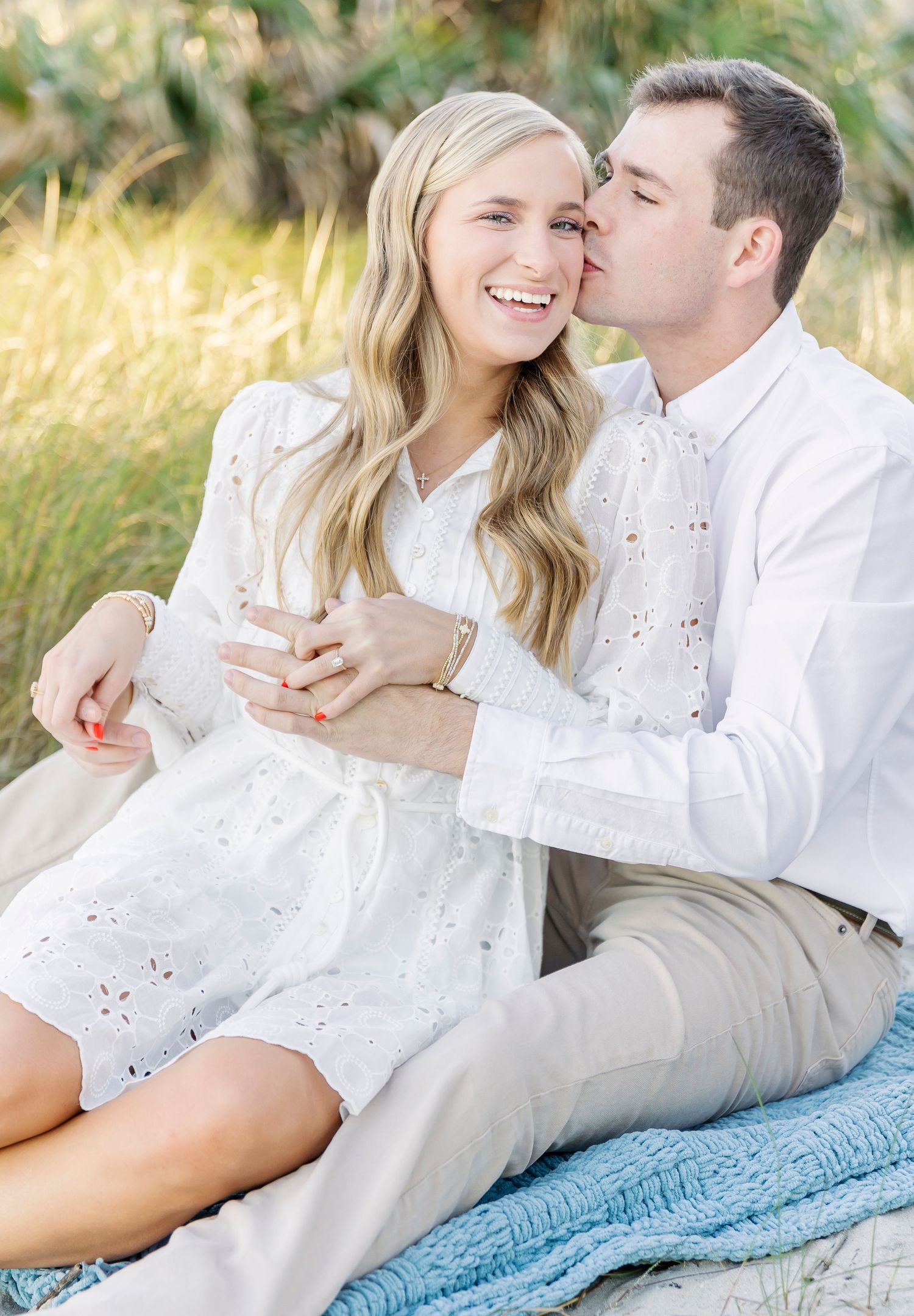A tender moment between a couple on a blanket surrounded by golden grass.