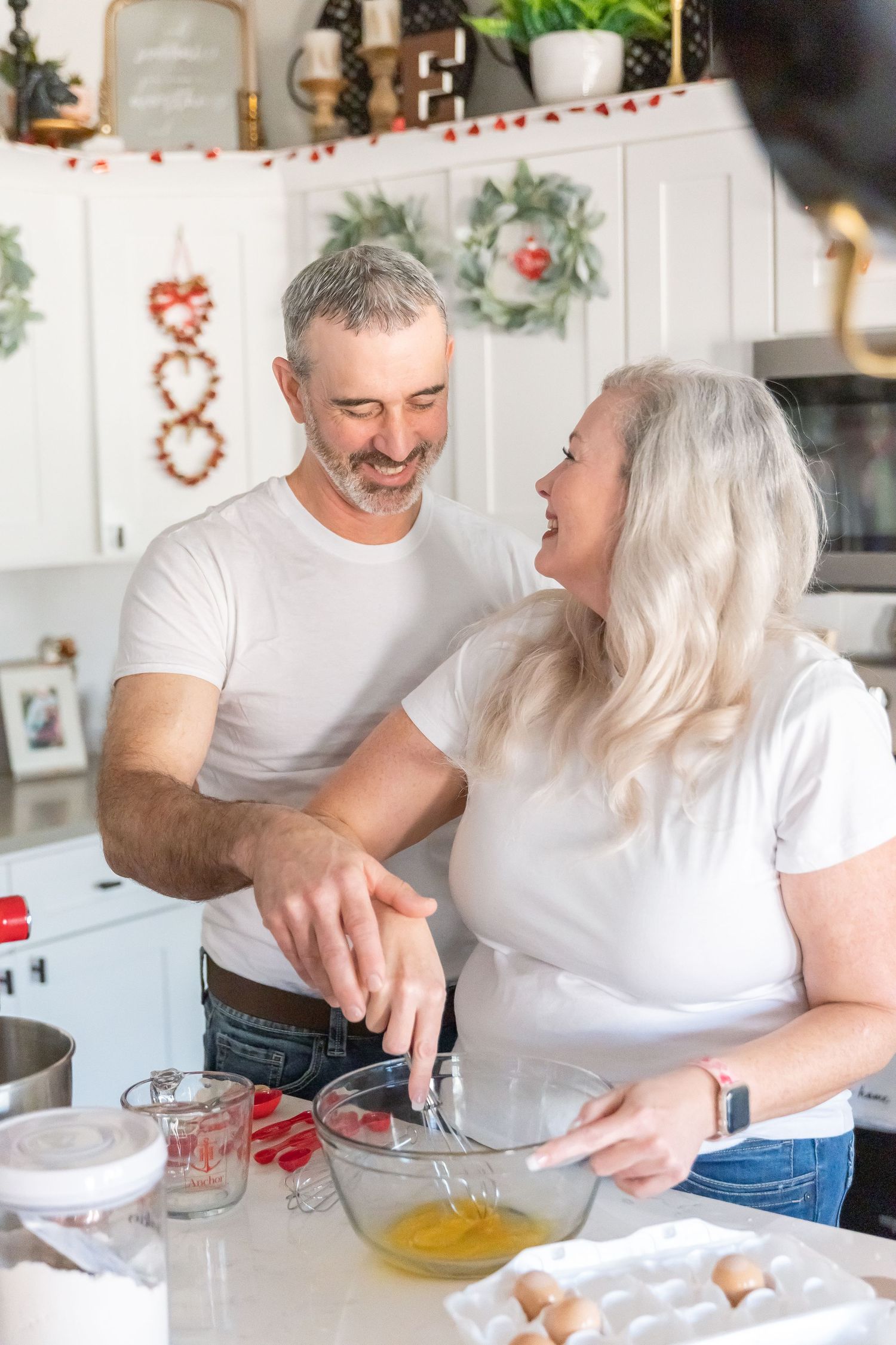 Couple sharing joyful moment while preparing holiday treats in decorated kitchen.