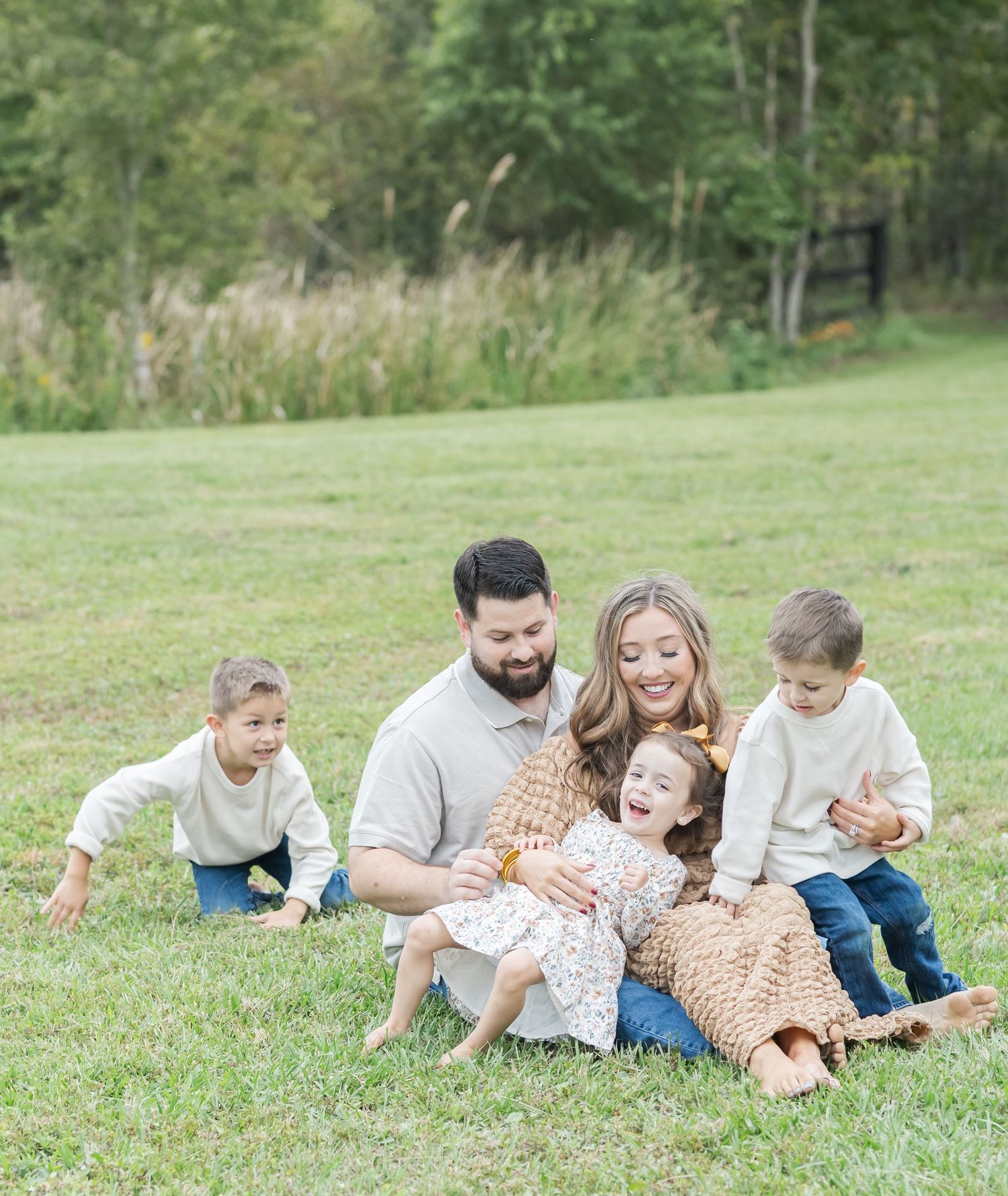 Family lies together on grass enjoying quality time outdoors.