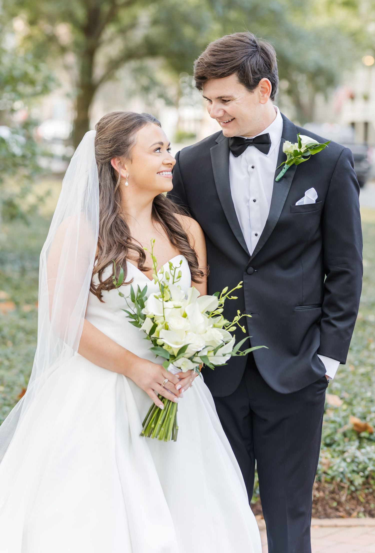 A bride and groom share candid moments in a garden setting while wearing traditional wedding attire.