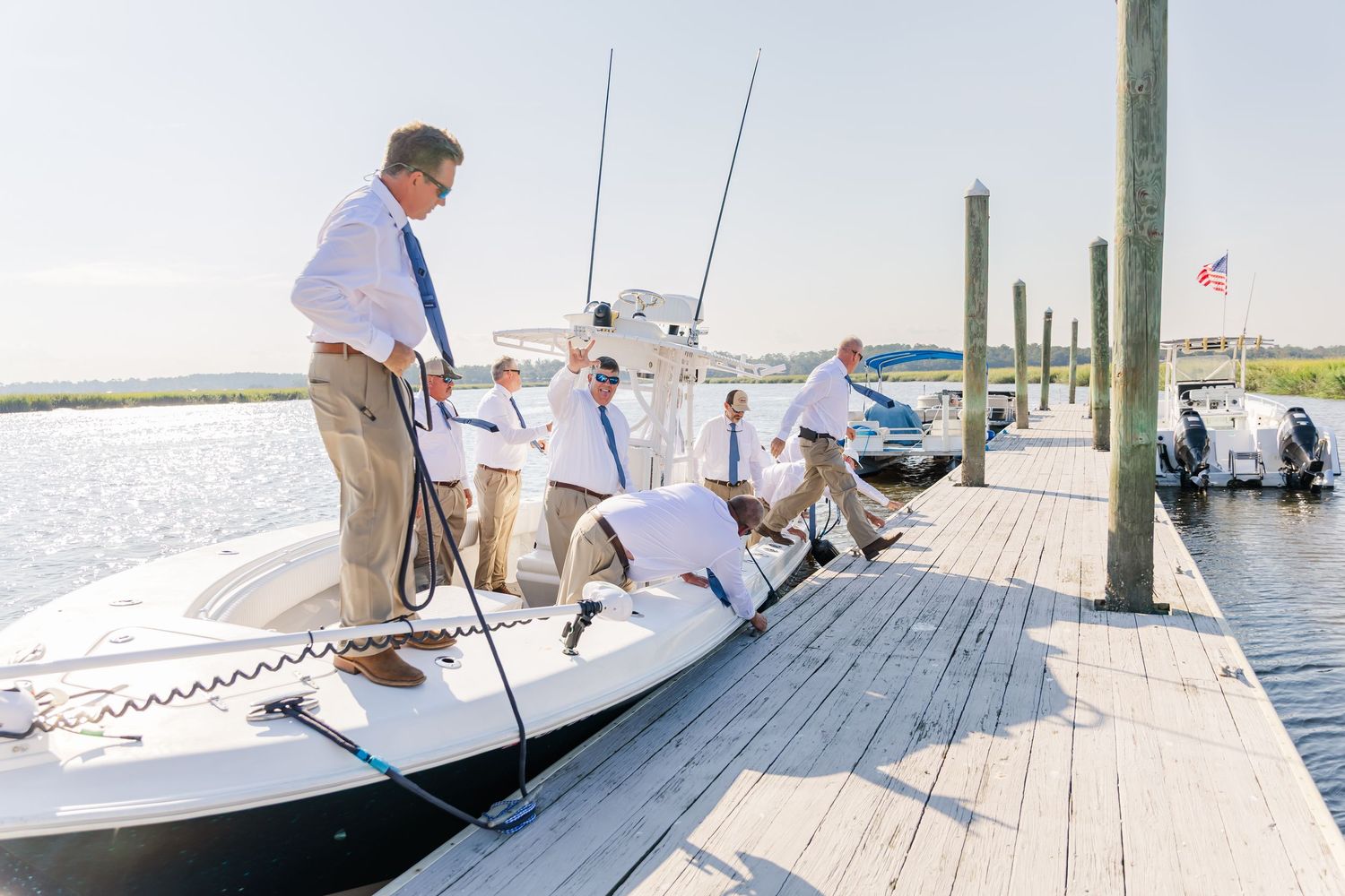 Group gathered on a wooden dock next to a moored boat on a bright summer day.