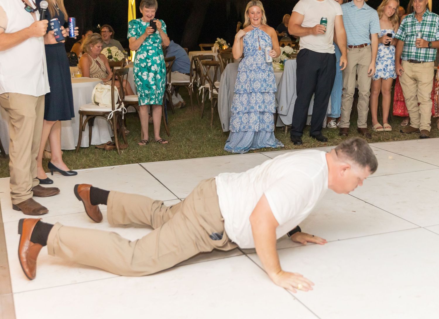 Wedding guests dance and celebrate on an outdoor dance floor during an evening reception.