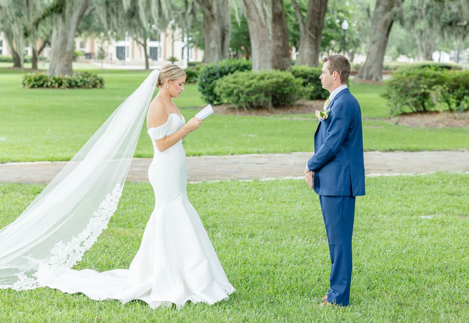 A romantic wedding couple shares tender moments in a lush garden setting with flowing white dress and navy suit.
