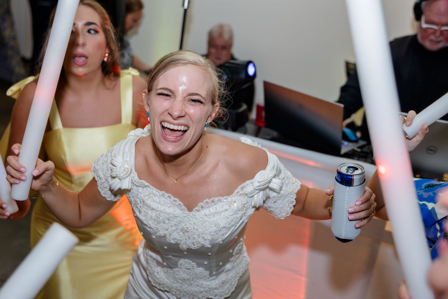 Wedding guests dance with glowing foam sticks during an energetic reception celebration.