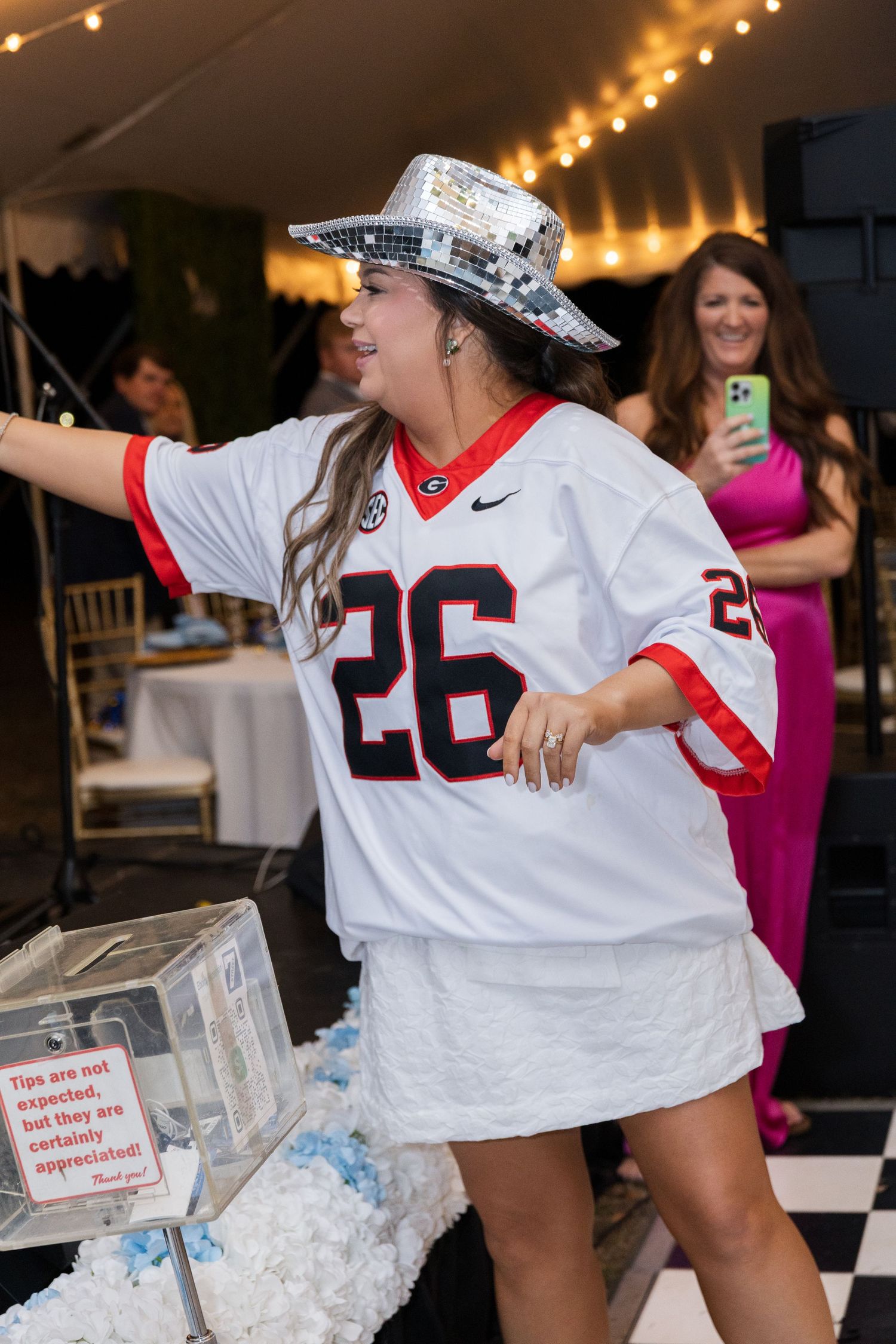 Bride changes into Georgia Bulldogs jersey and disco cowboy hat to dance at wedding reception.