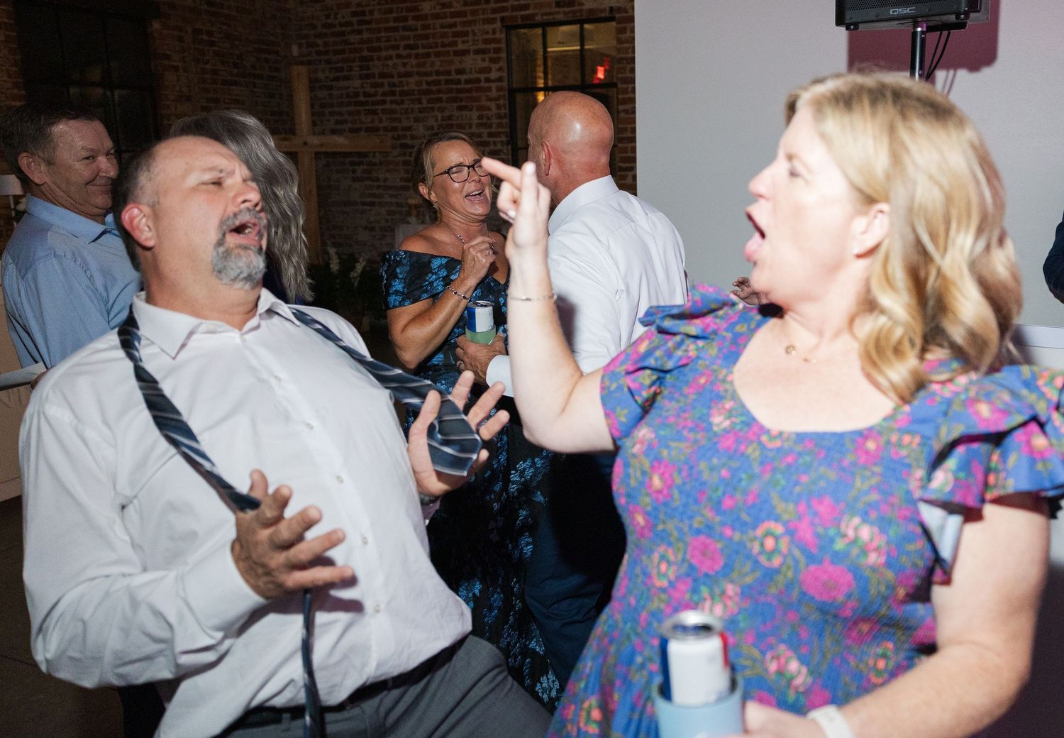Guests laughing and dancing energetically together at lively wedding reception party celebration.