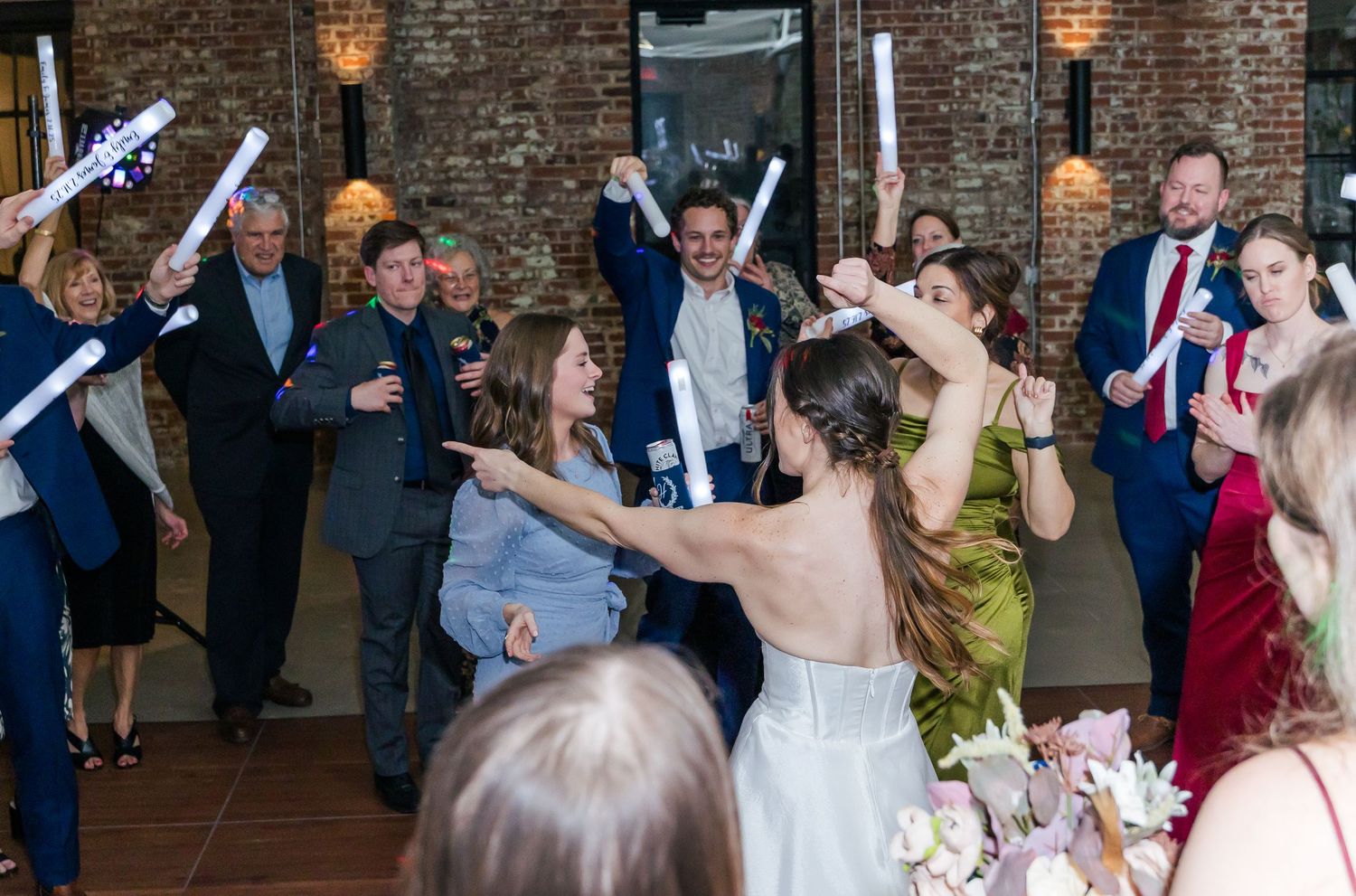 Wedding guests hold sparklers during an outdoor nighttime send-off celebration on brick pavers.