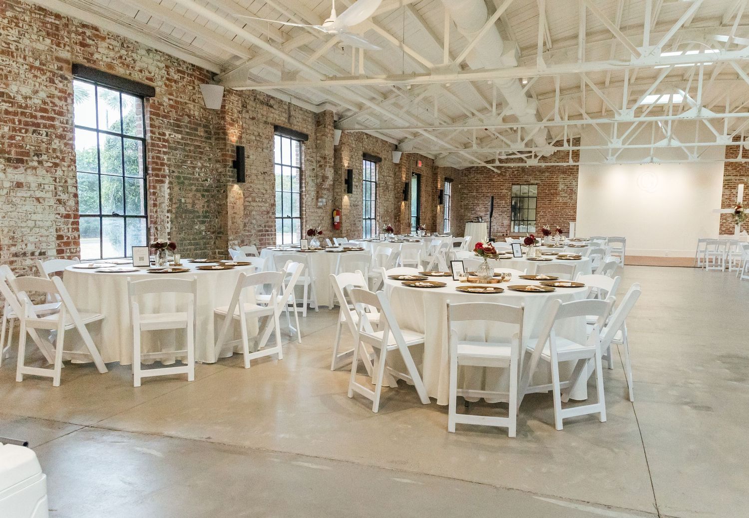 Industrial chic wedding venue with exposed brick walls, white chairs and natural lighting.