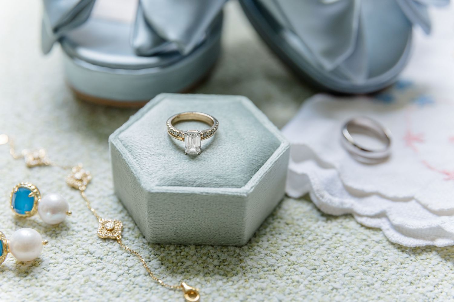 Diamond engagement ring in gray hexagonal box with scattered decorative elements.