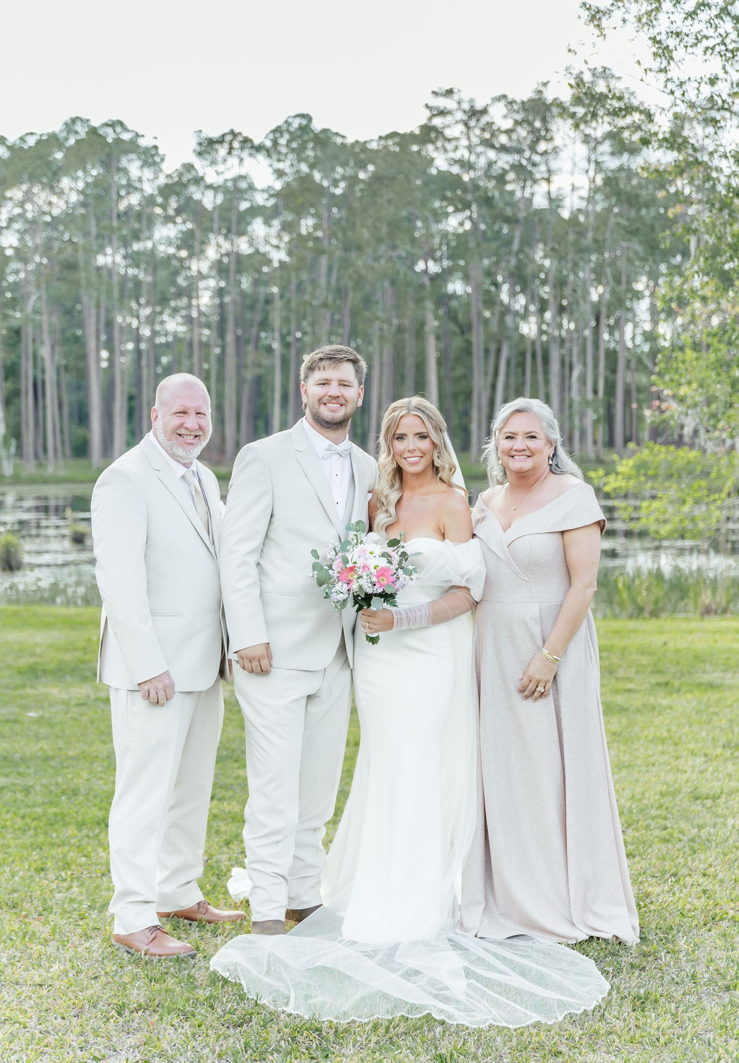 Family portrait in coordinated white attire against a backdrop of pine trees and lake.