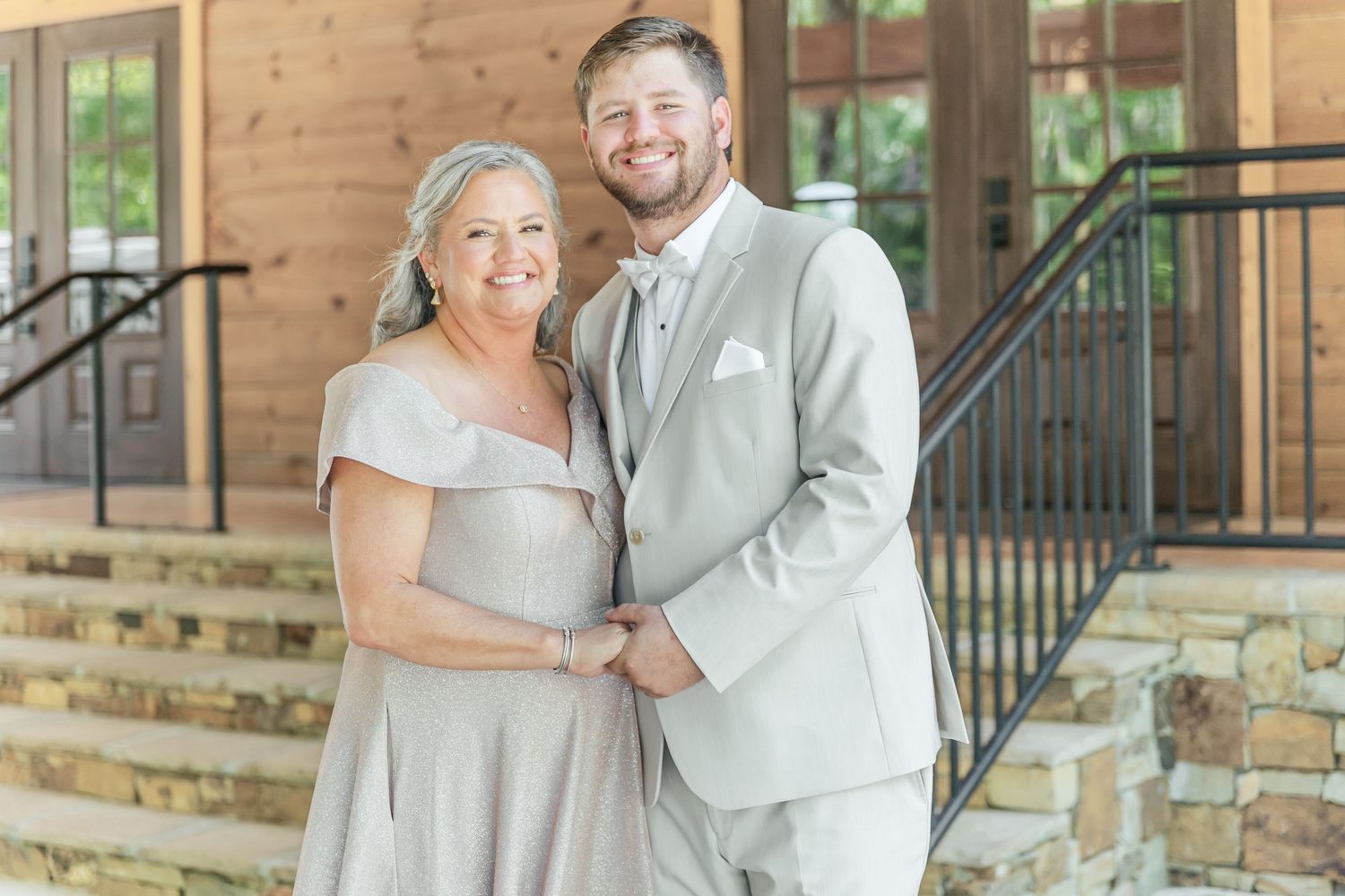 Two people in matching formal grey attire pose together on stone steps.