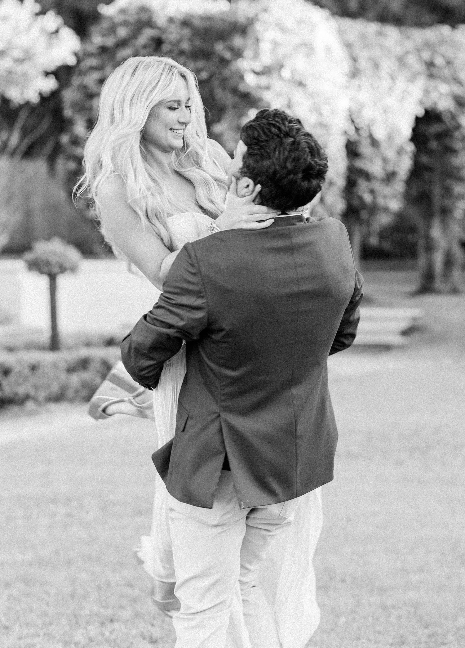A tender black and white moment captured of a couple in an intimate embrace outdoors.