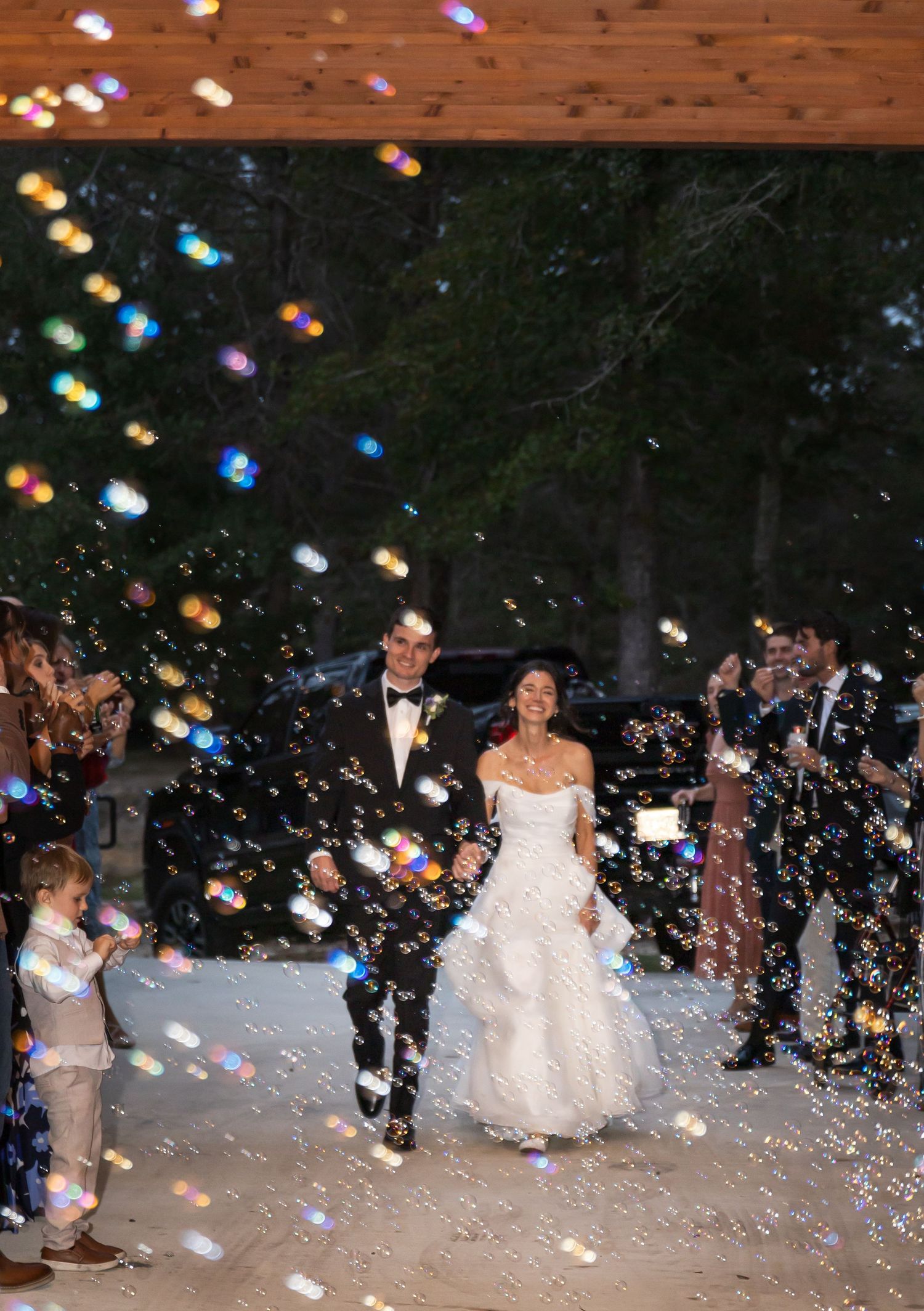 A couple walks through a magical shower of colorful bubbles during their outdoor wedding exit.