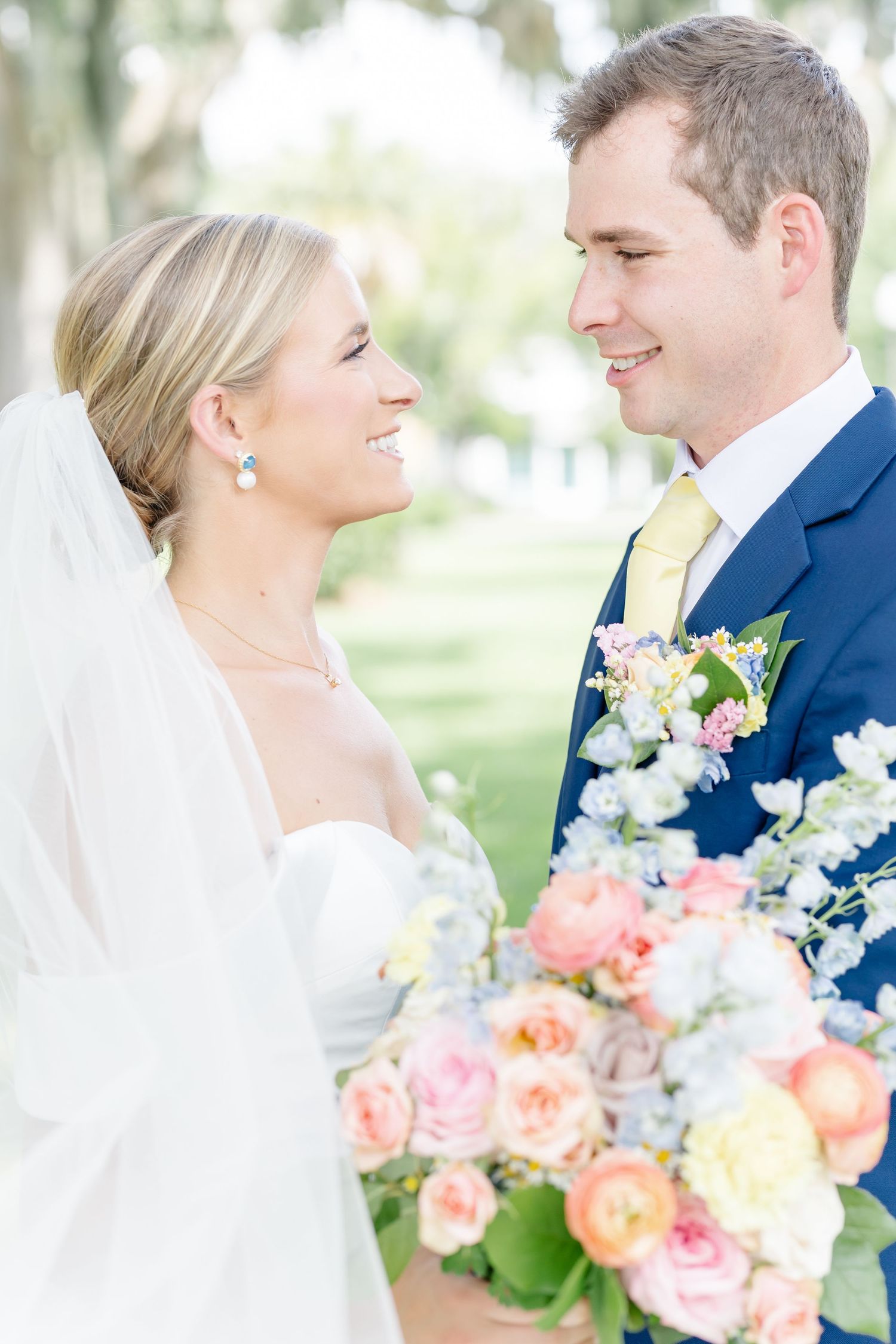 A romantic wedding moment outdoors with a beautiful bouquet of pink and blue flowers against a soft natural background.