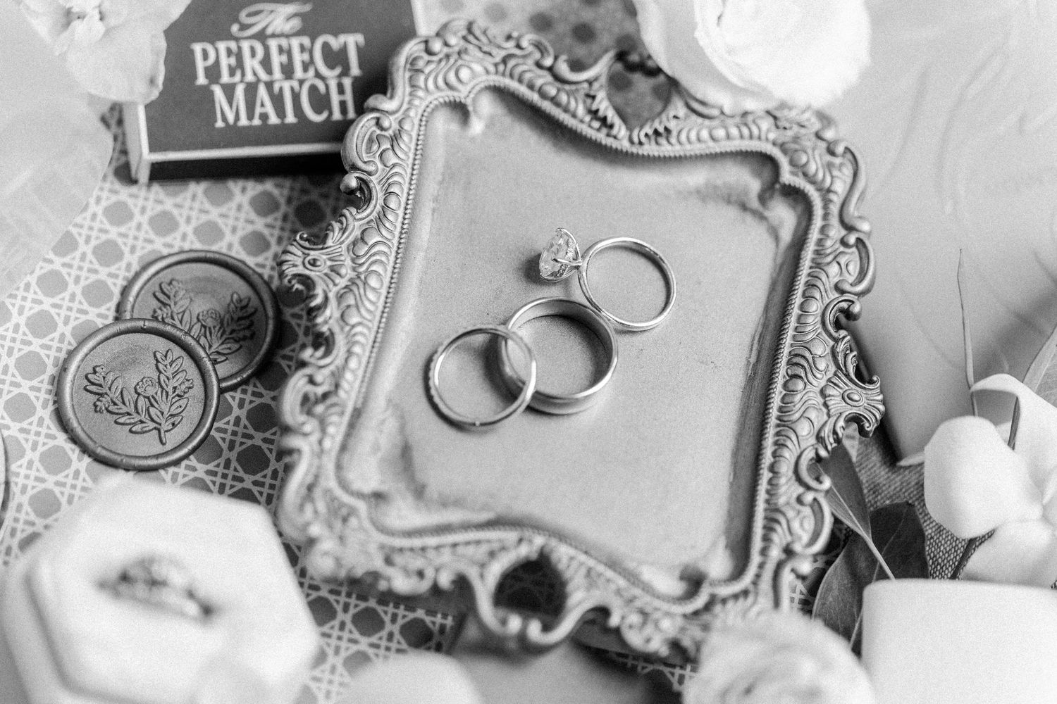 Wedding rings and delicate lace details create an elegant monochromatic composition in soft gray tones.