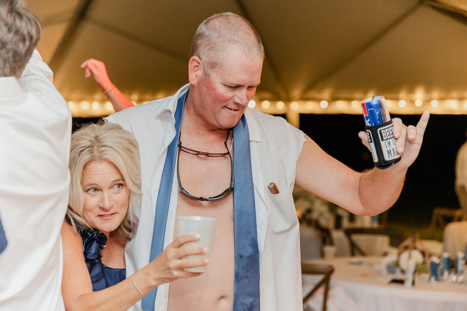 Wedding guests enjoying themselves on a dance floor with blue decorative accents at an outdoor reception.