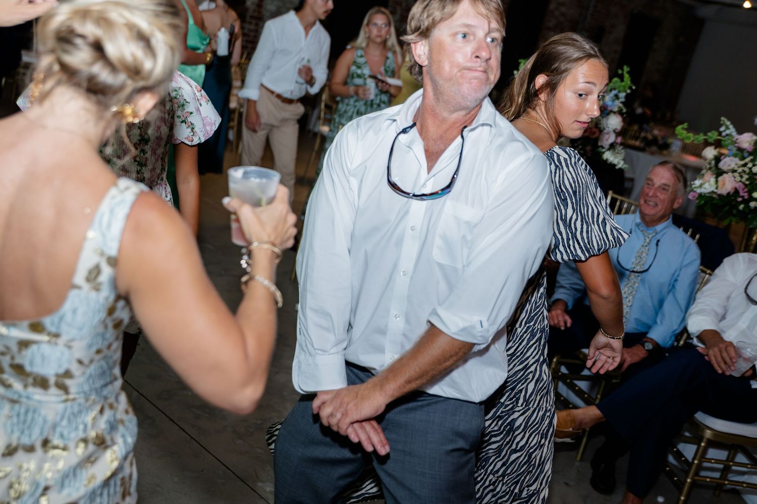 Dancers enjoying themselves at a lively wedding reception with string lights and exposed brick walls.