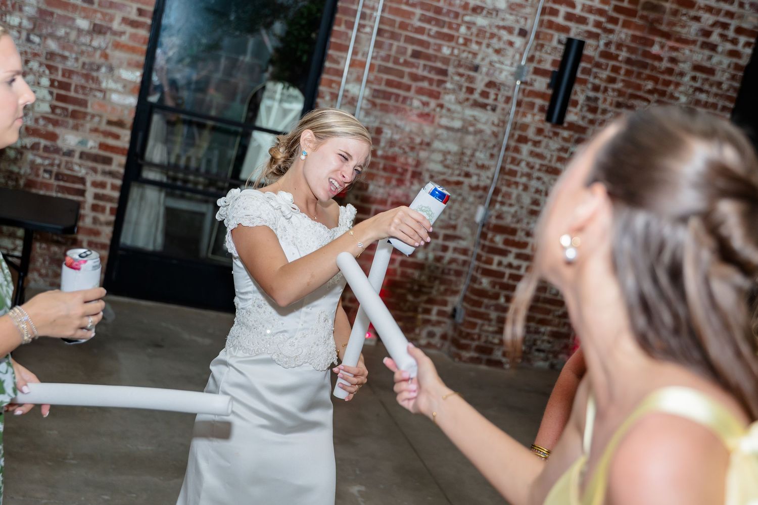 People celebrating at a wedding reception in a rustic brick venue with drinks and dancing.