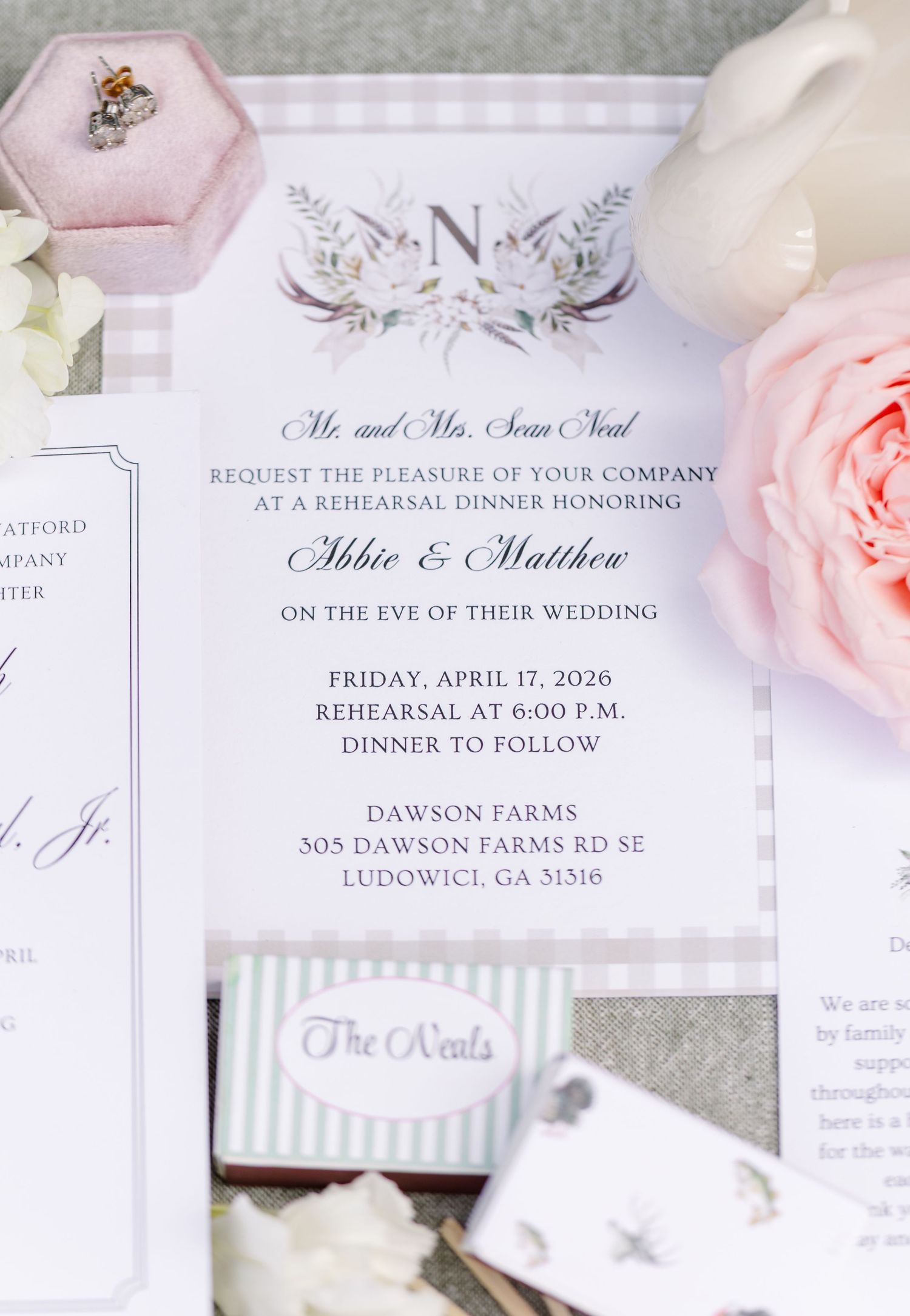 Elegant rehearsal dinner invitation for Abbie & Matthew at Dawson Farms, featuring floral crest design with pink roses and ring box.