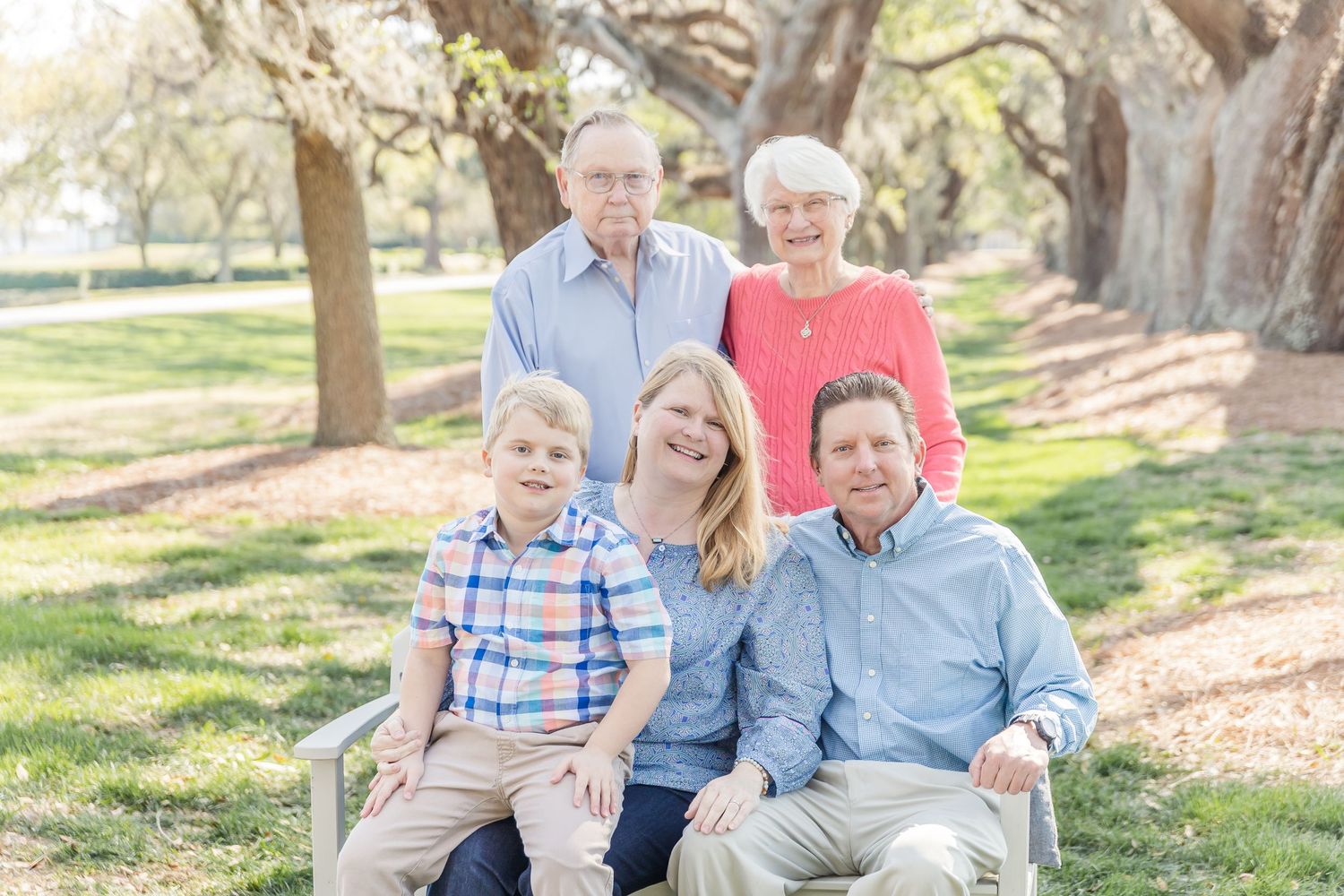 Family portrait with five members sitting together under oak trees with Spanish moss.