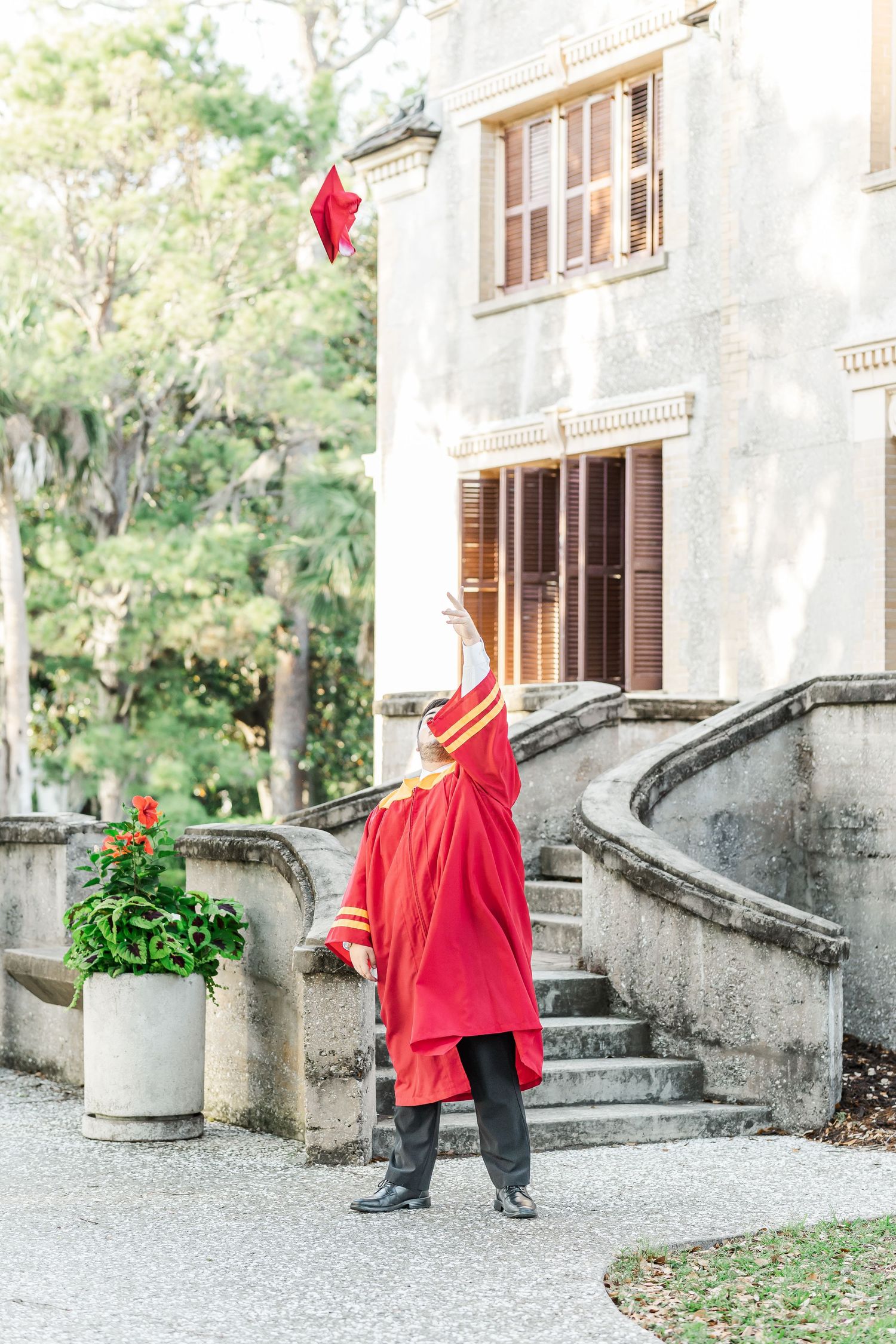 Children dressed in bright red jackets play in front of a stone building with elegant architecture.