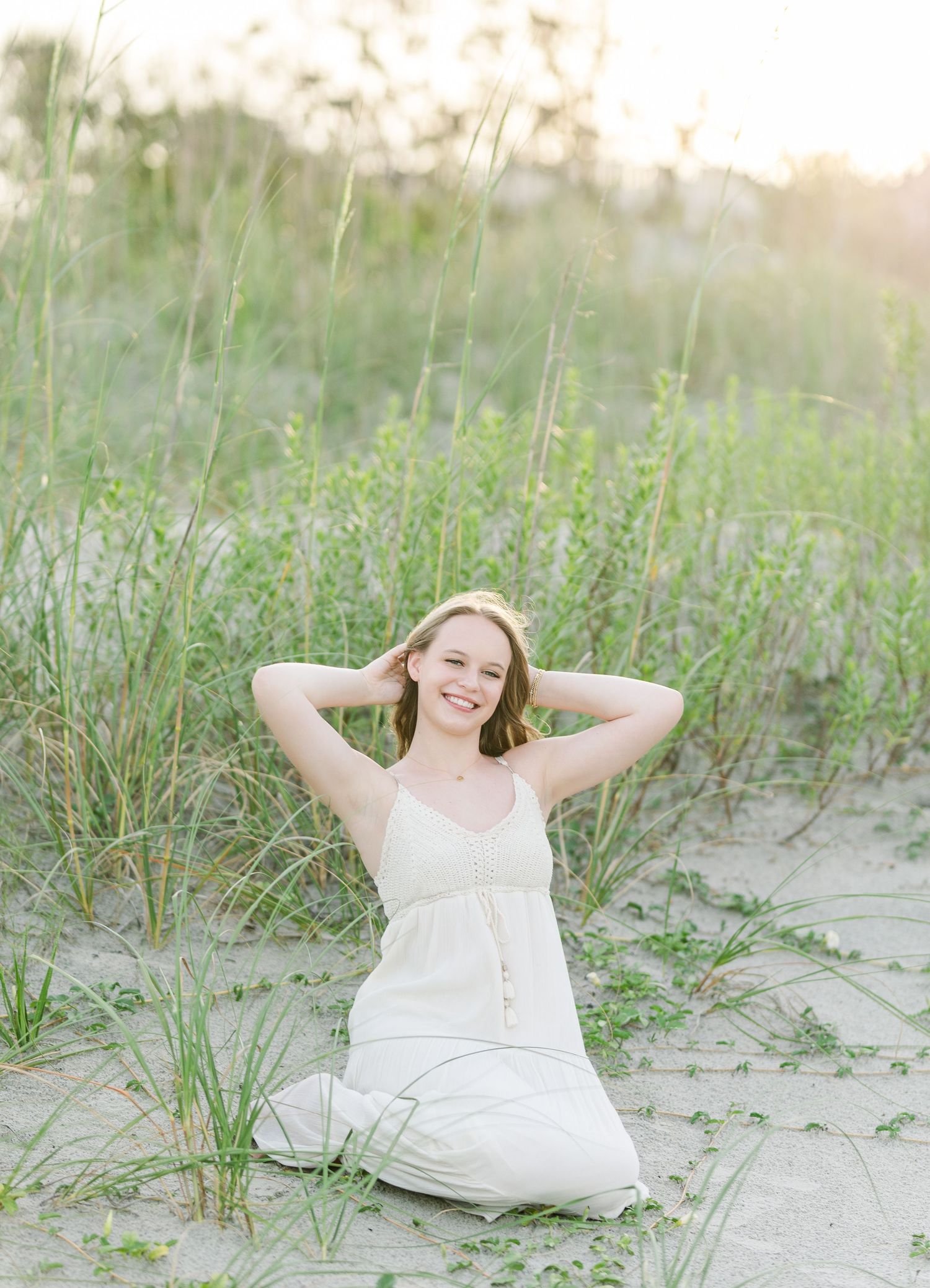 A sunny beach scene with tall dunes and sea grasses providing a natural backdrop.