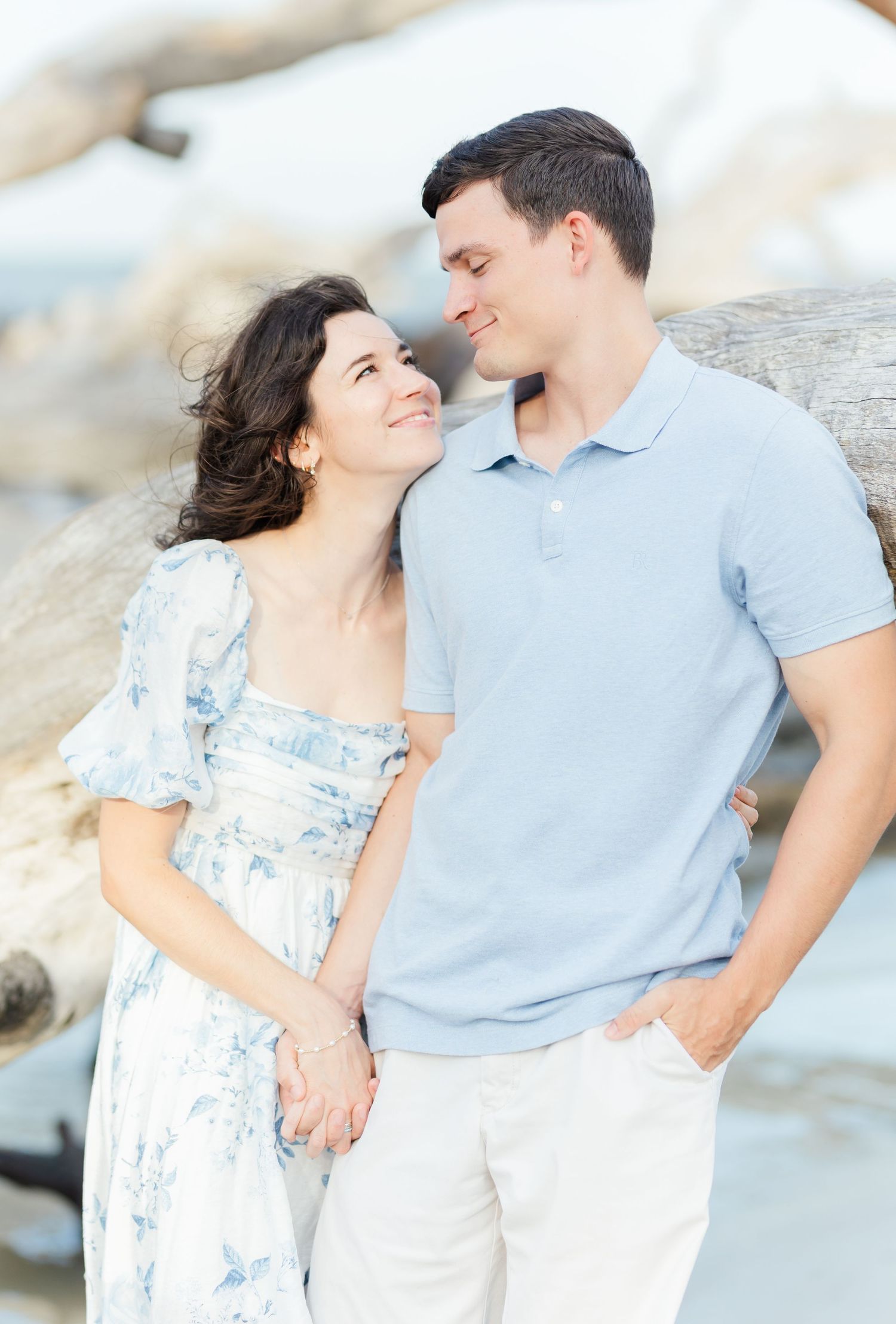 Romantic couple in light blue and white share intimate moments against bright beach backdrop.
