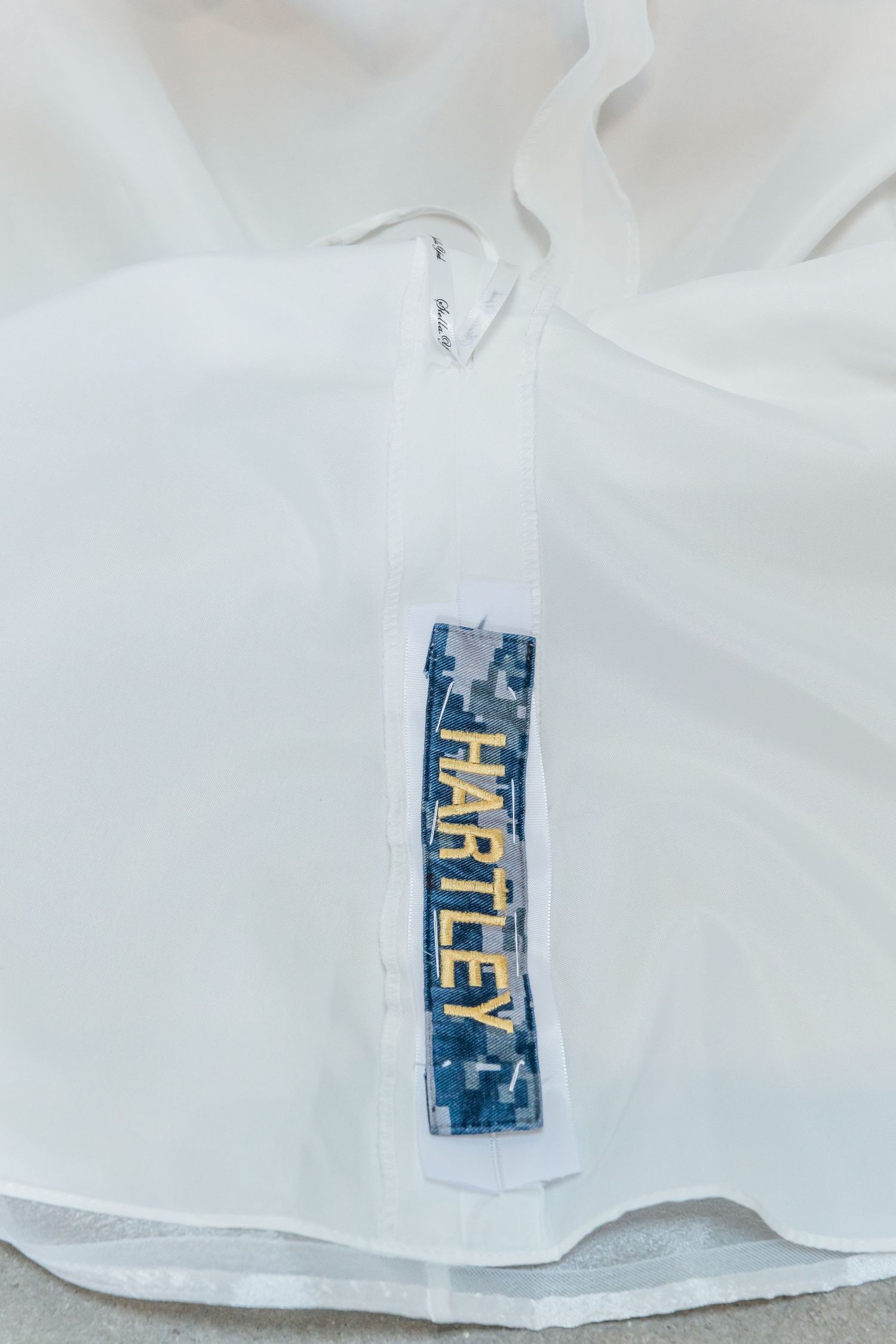 Detail shots of a blue and gold clothing label tag attached to a white garment shown from different angles.
