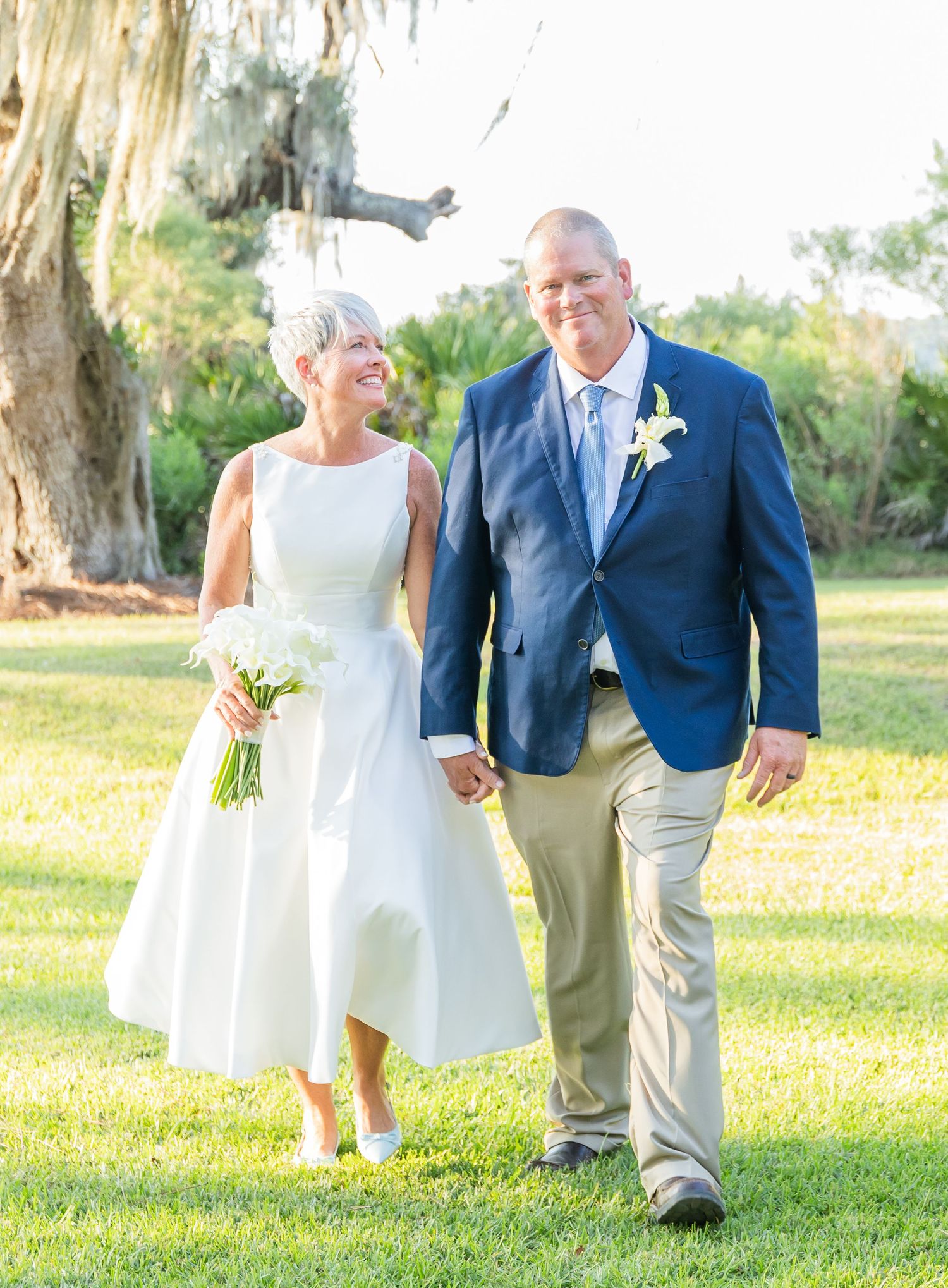 A couple walks together on a sunny lawn, captured in a series of candid moments in their wedding attire.