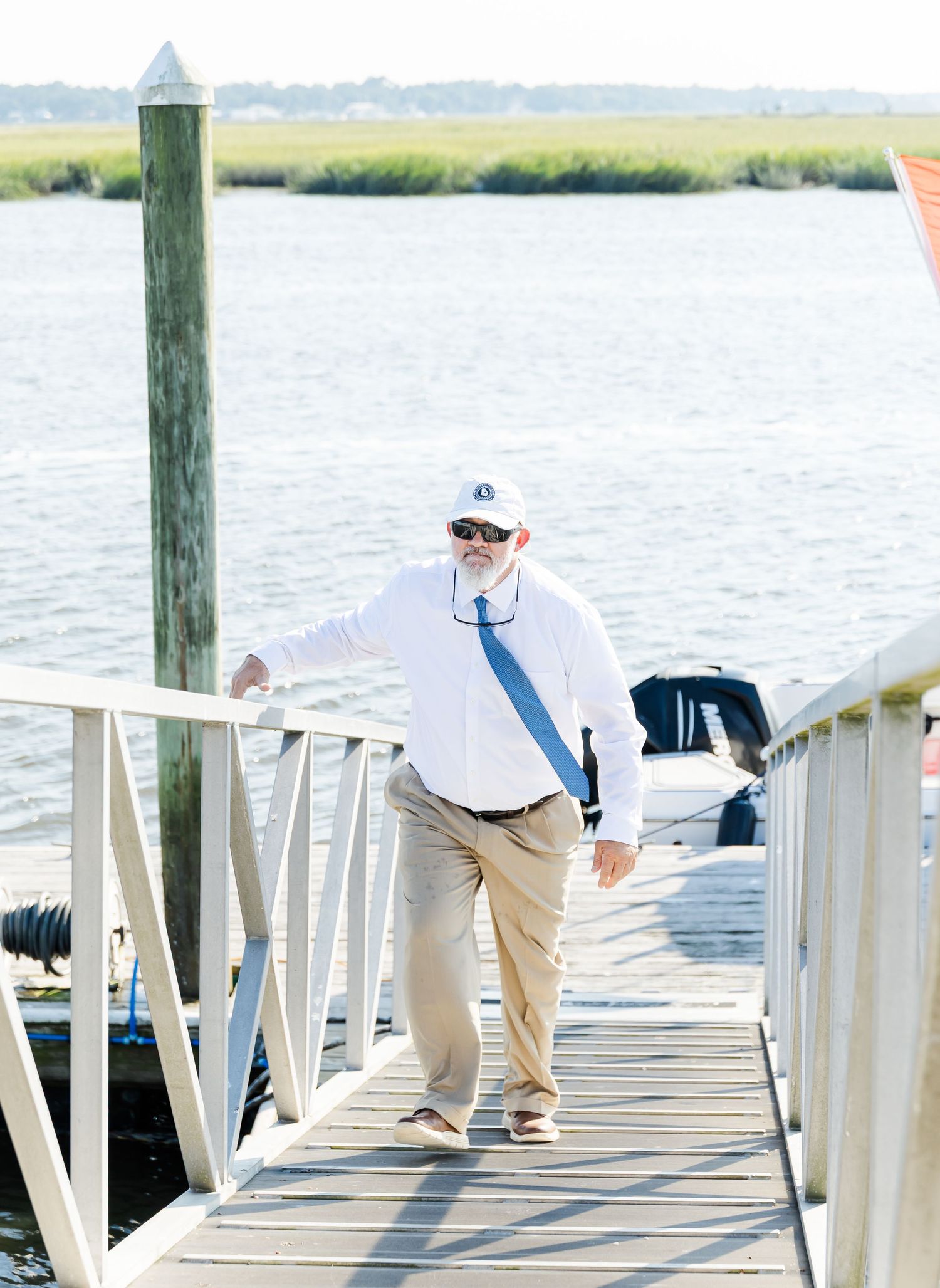 People walking down a wooden dock extending over peaceful coastal waters.